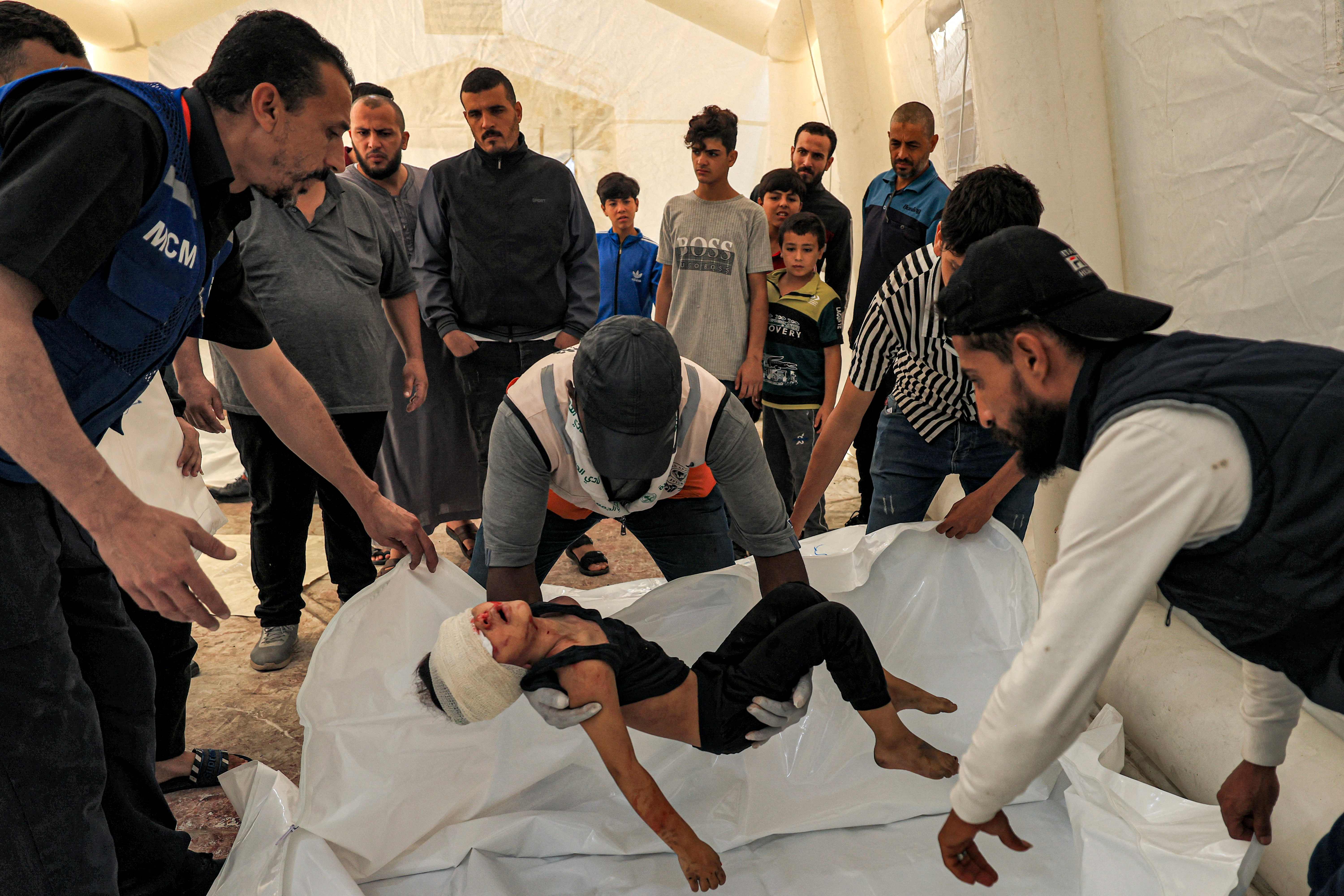 Relawan membaringkan tubuh seorang anak yang tewas karena serangan roket Israel, di Rumah Sakit Al-Shifa, Gaza, Kamis (12/10).