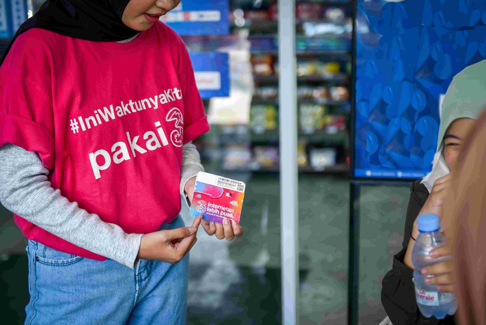 Petugas mendistribusikan kartu perdana Tri kepada warga.