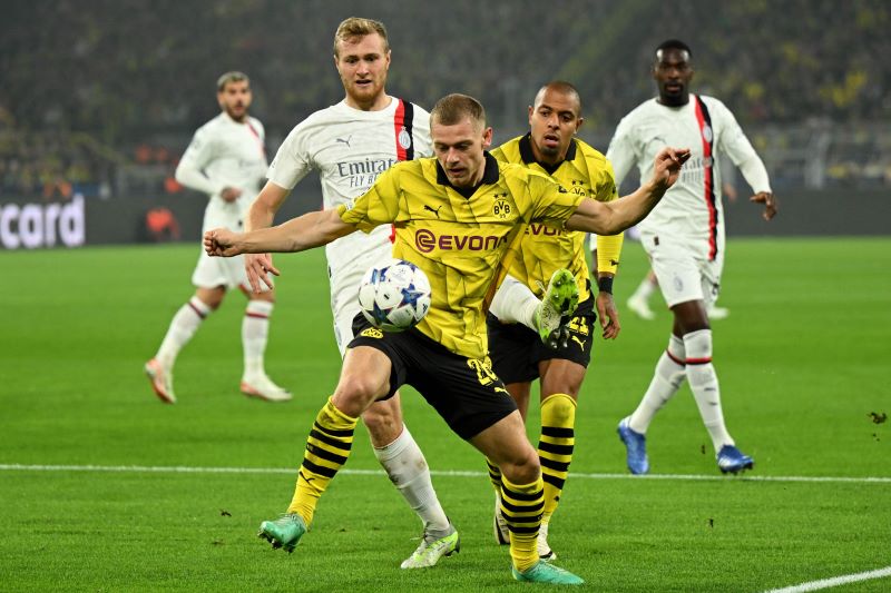 Pemain Dortmund sedang mempertahankan bola dari pemain AC Milan.