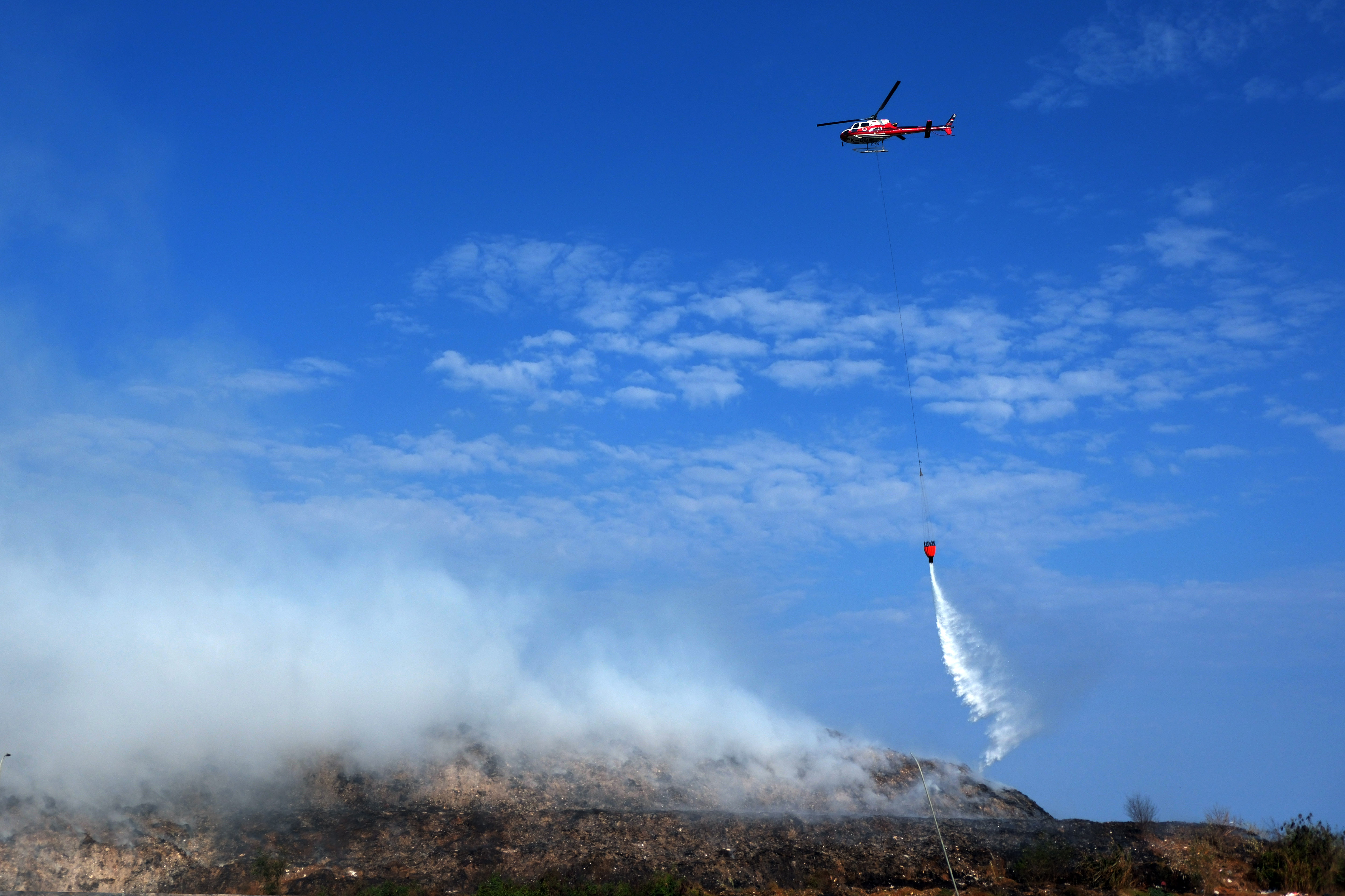 Helikopter BNPB menumpahkan air untuk memadamkan kebakaran sampah di TPA Suwung, Denpasar, Bali, Jumat (13/10).