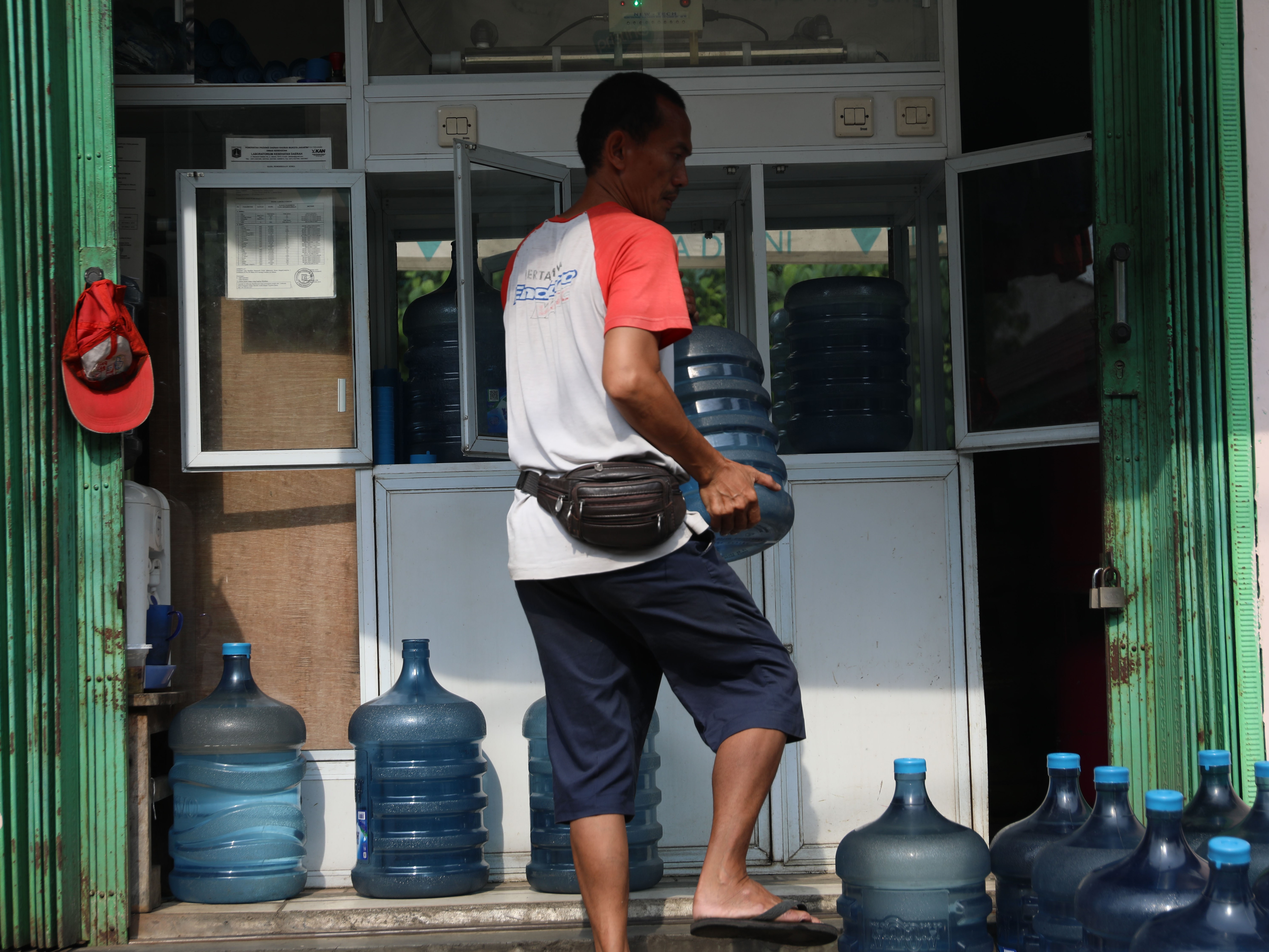 Penjual mengisi botol galon air isi ulang di Kedoya, Jakarta Barat, Senin (4/9/2023). 