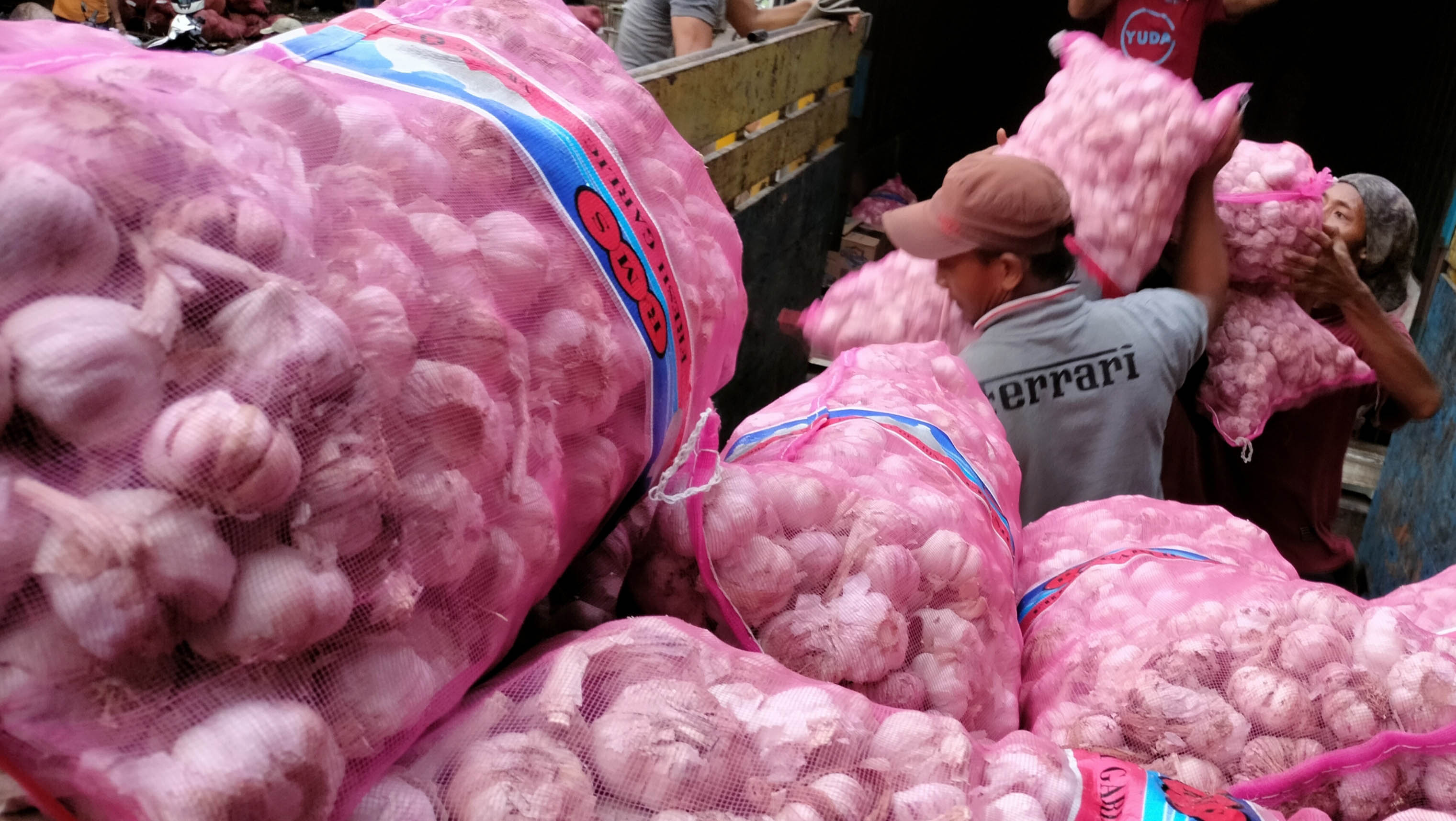 Pekerja memindahkan karungan Bawang Putih dari Truk Kontaner ke truk yang akan membawa ke daerah tujuan di Ps Induk Kramat Jati, Jaktim.