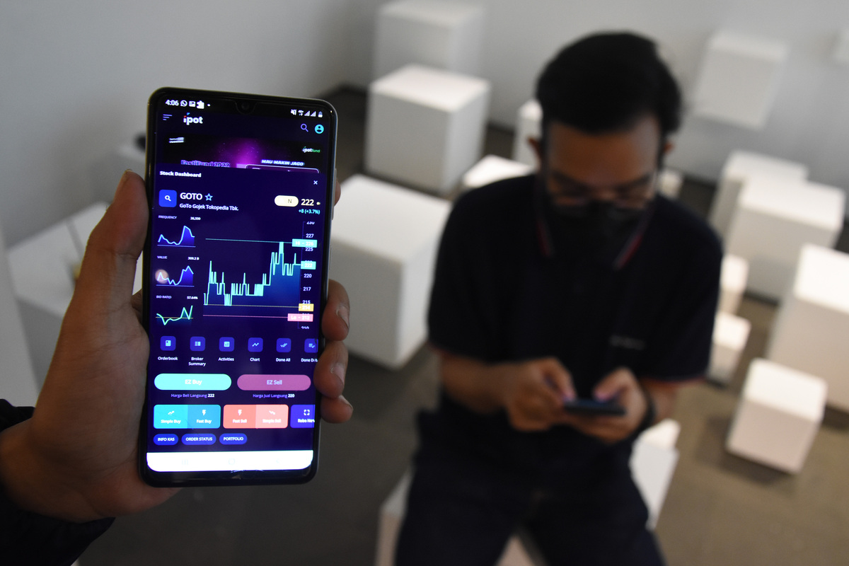Pekerja melihat pergerakan saham GoTo (Gojek Tokopedia).