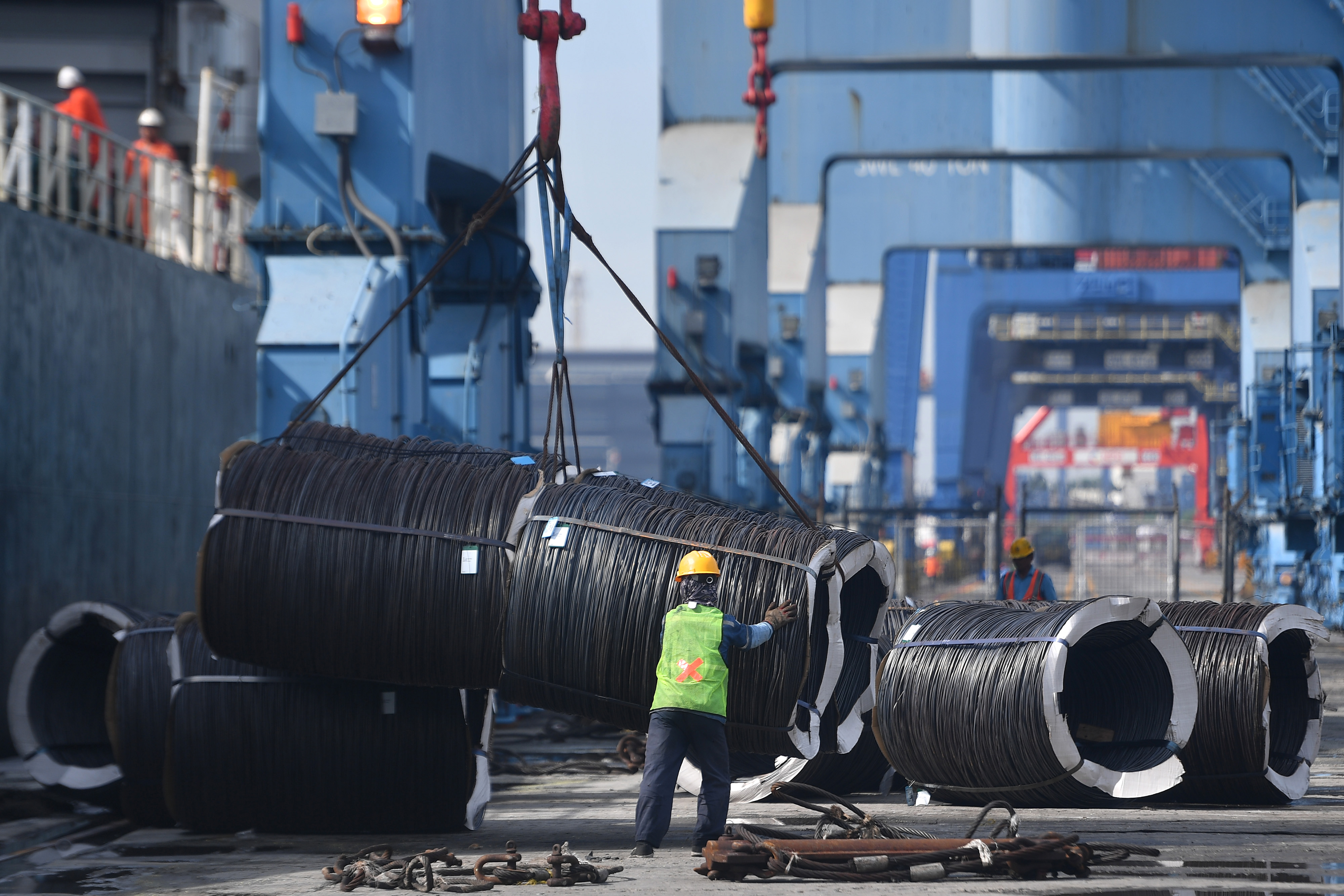 Pekerja membantu bongkar muat gulungan besi baja di Pelabuhan Tanjung Priok, Jakarta Utara.