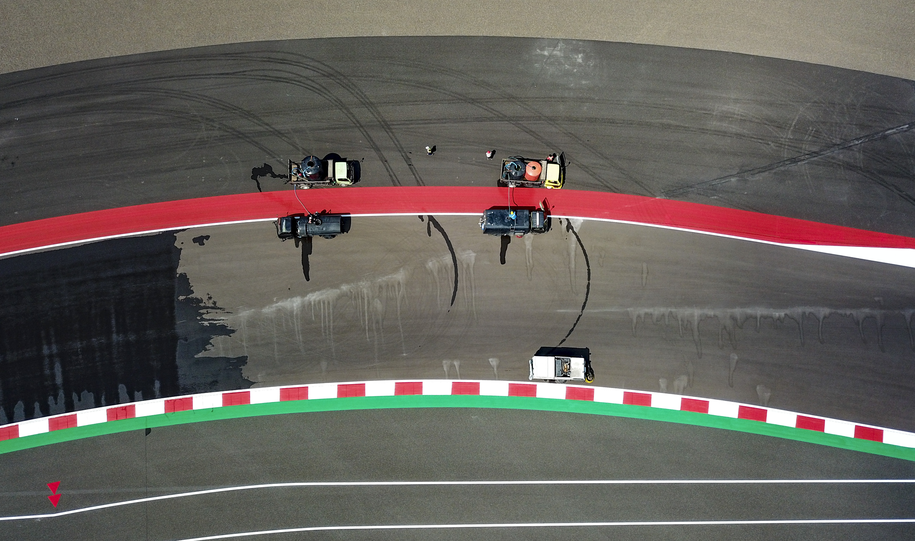 Foto udara sejumlah petugas menggunakan mobil khusus membersihkan lintasan sirkuit Pertamina Mandalika International Street Circuit.