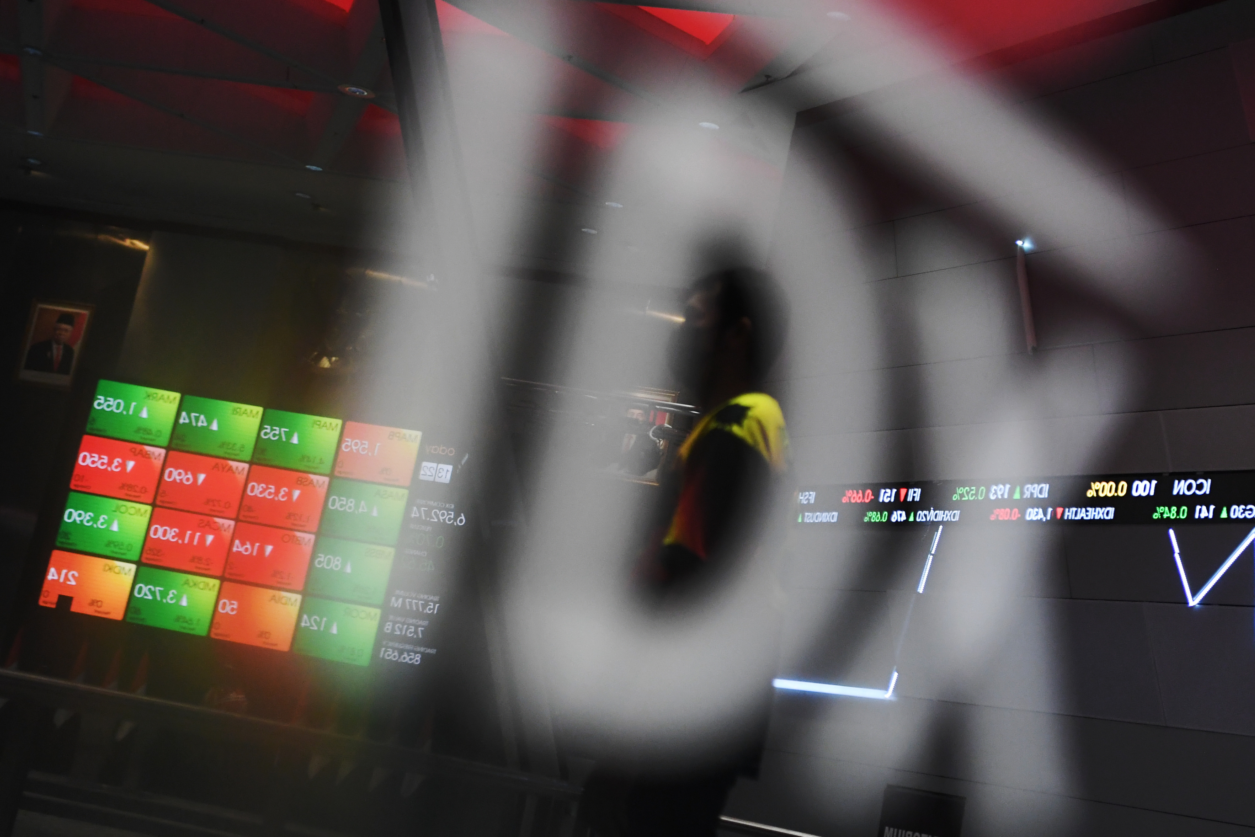 Pegawai melintas di dekat monitor pergerakan indeks harga saham di Bursa Efek Indonesia, Jakarta, Selasa (7/12/2021).