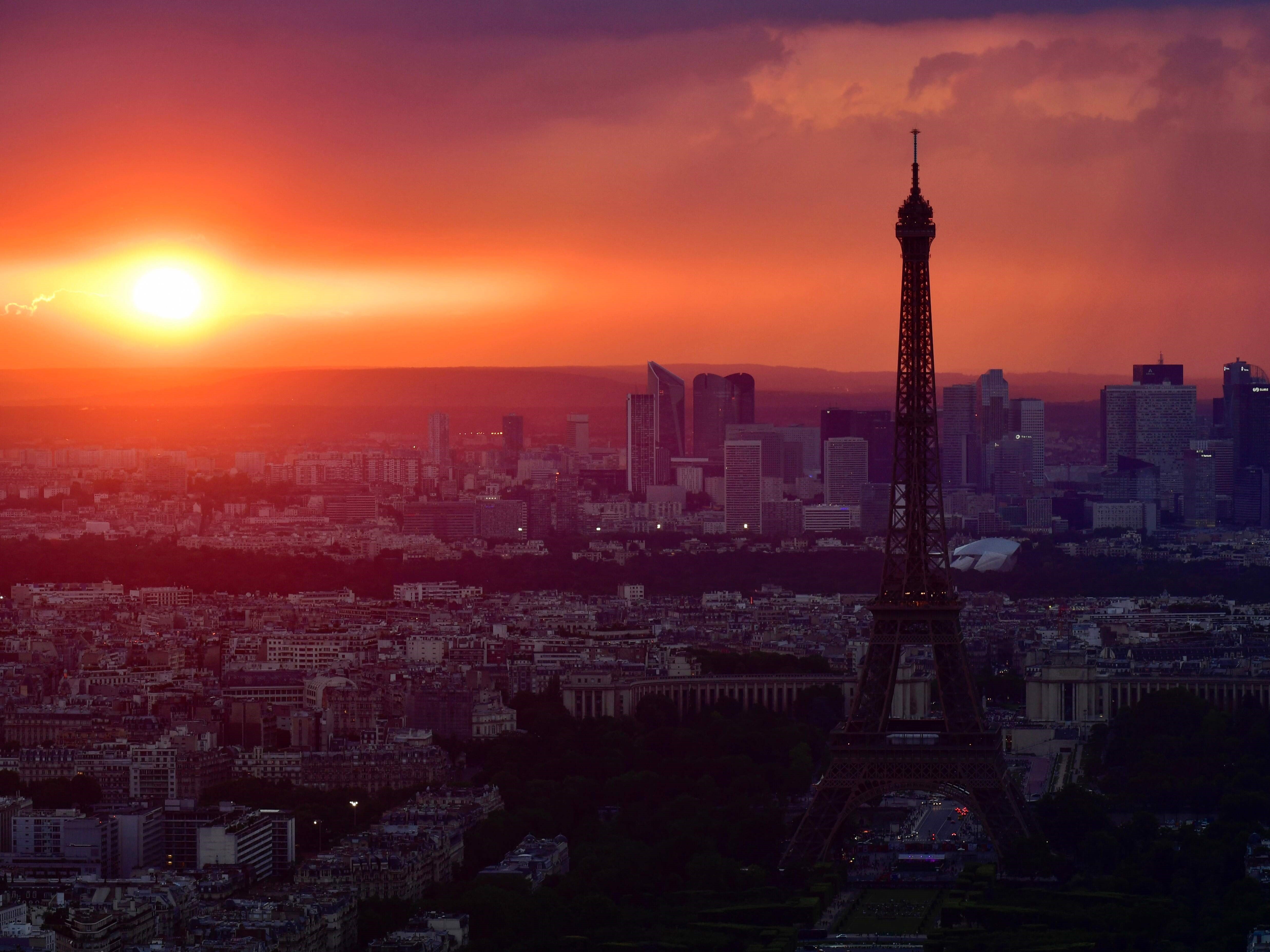 Menara Eiffel di Paris dan kawasan bisnis La Defense di bawah awan tebal saat matahari terbenam.