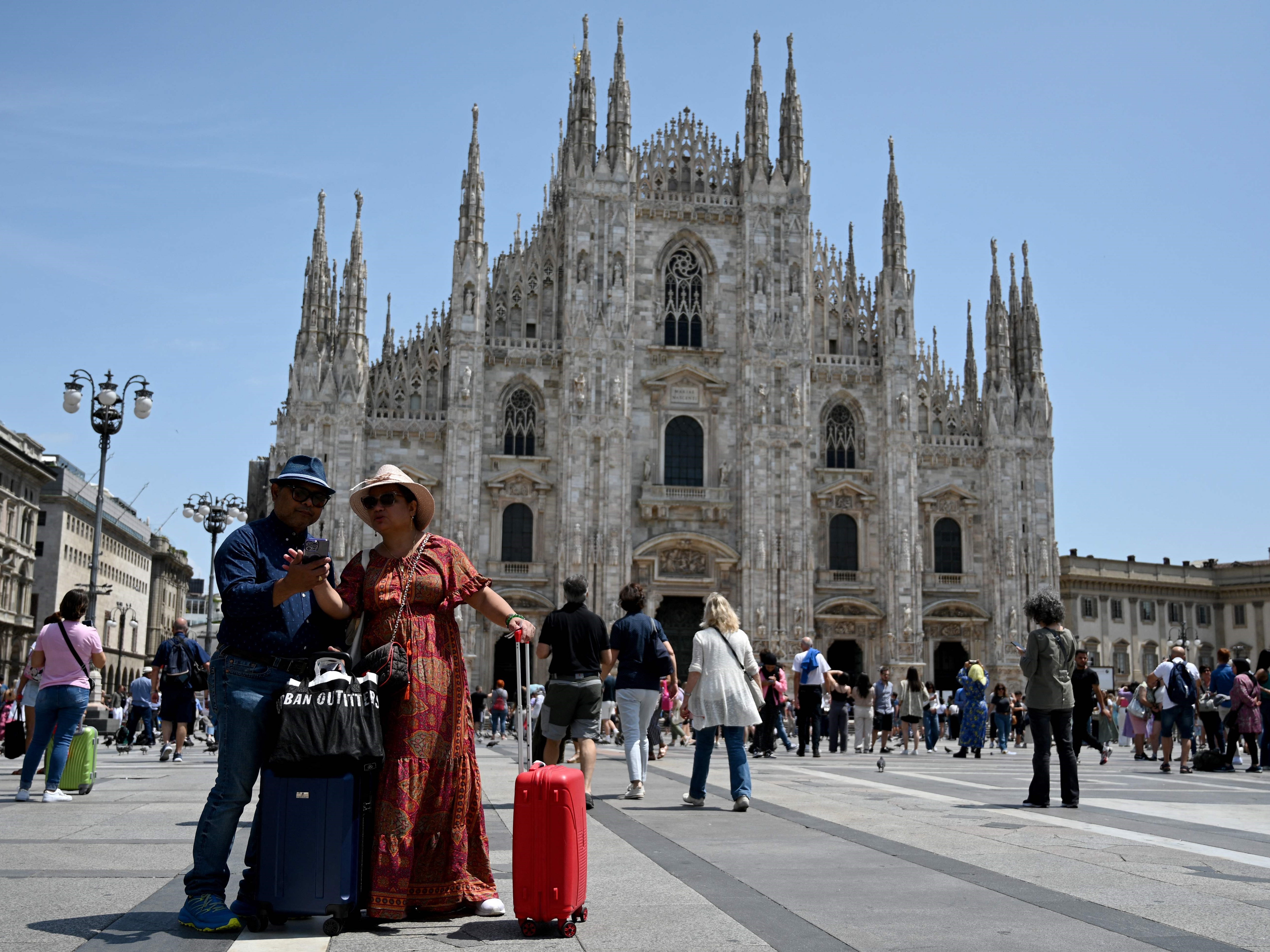 Wisatawan bersiap berpose untuk selfie di depan Katedral Duomo di Milan pada 6 Juli 2023.