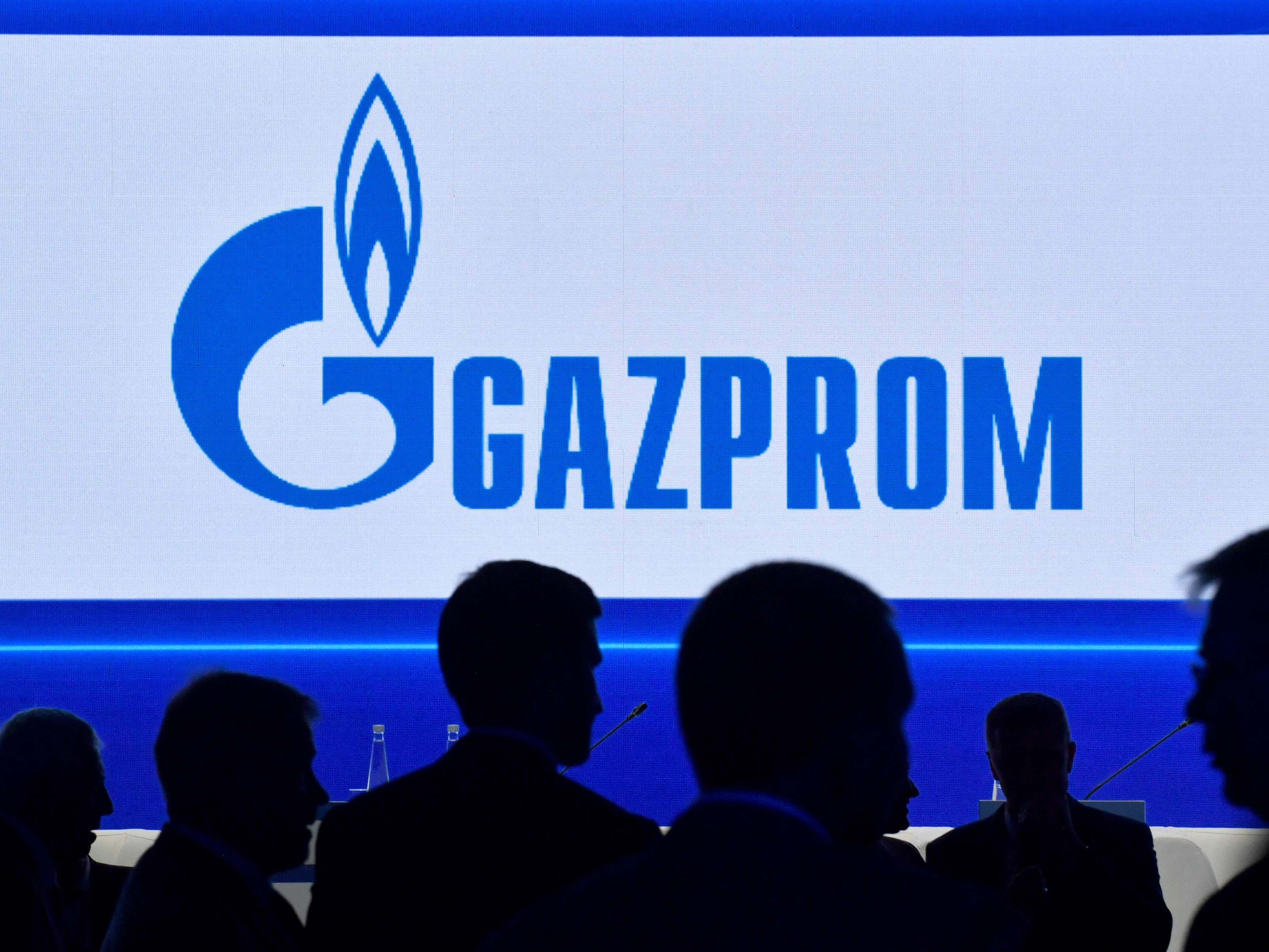 Peserta berjalan di depan layar besar yang menampilkan logo raksasa energi Rusia Gazprom selama Forum Gas Internasional St. Petersburg.
