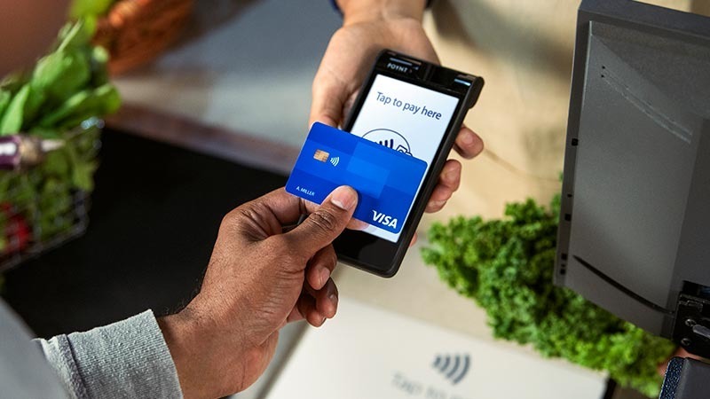 Pengguna kartu kredit Visa bertransaksi dengan menggunakan kartu tersebut.