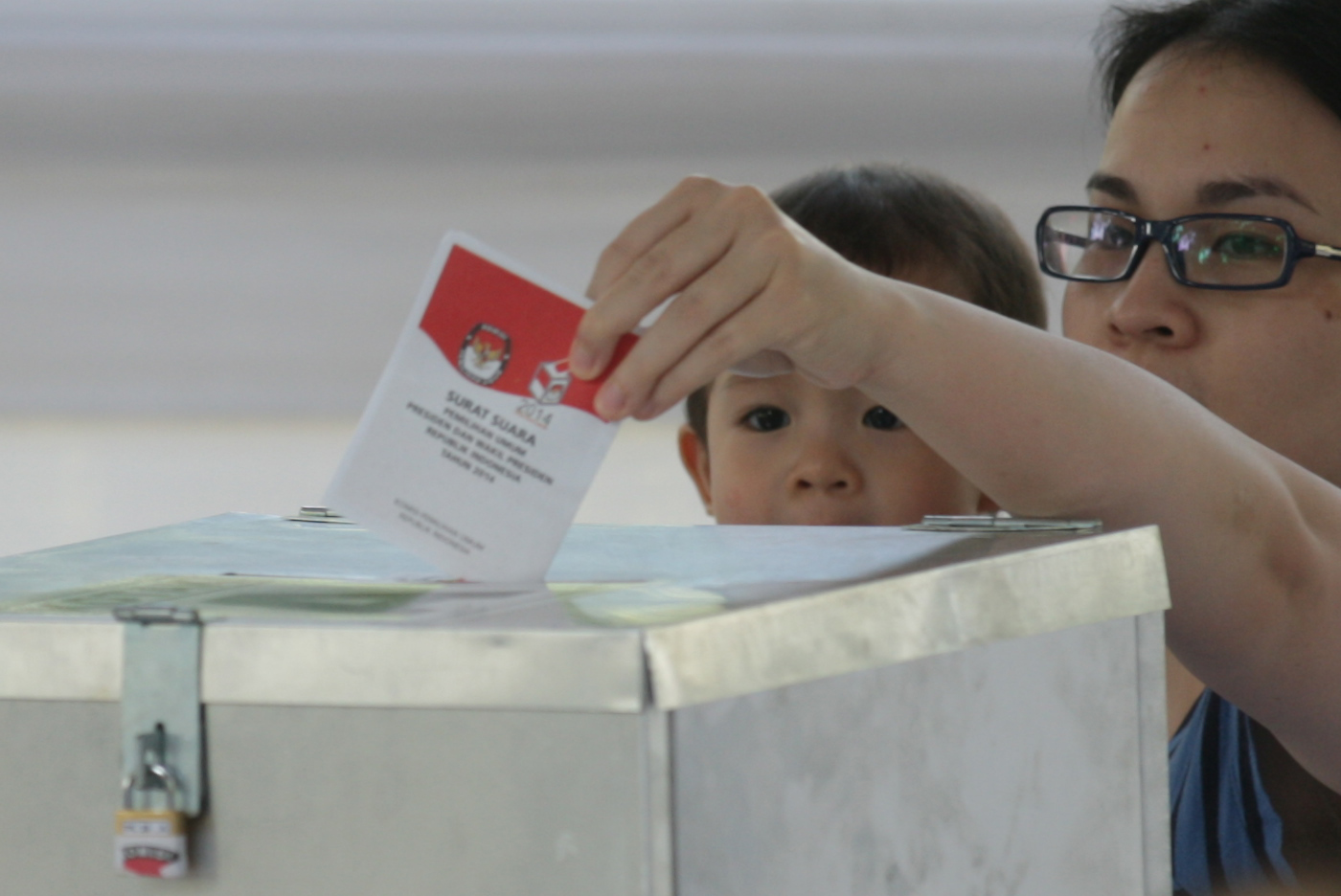 Seorang bocah mengamati surat suara yang dimasukkan ibunya kedalam kotak suara saat menggunakan hak pilihnya di TPS.