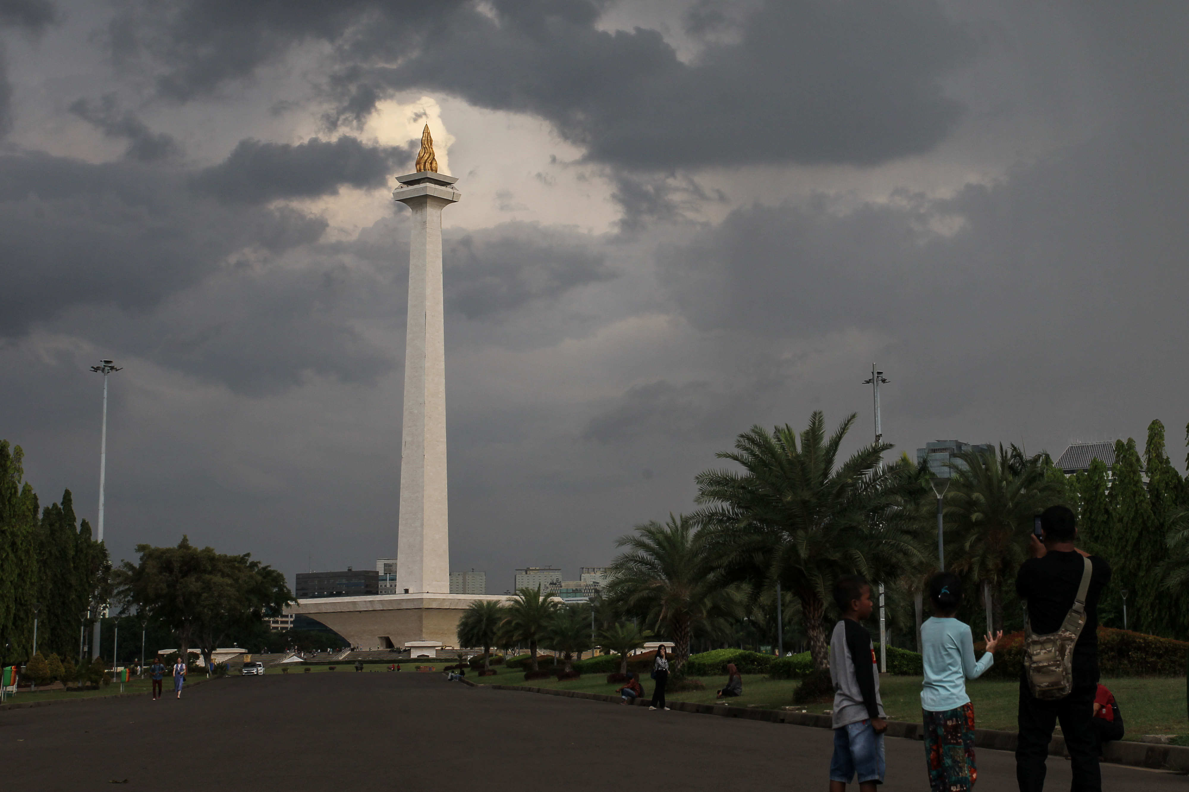 Pengunjung menikmati kawasan wisata Monas yang dipenuhi awan mendung, Jakarta, kamis (15/11/2018). 