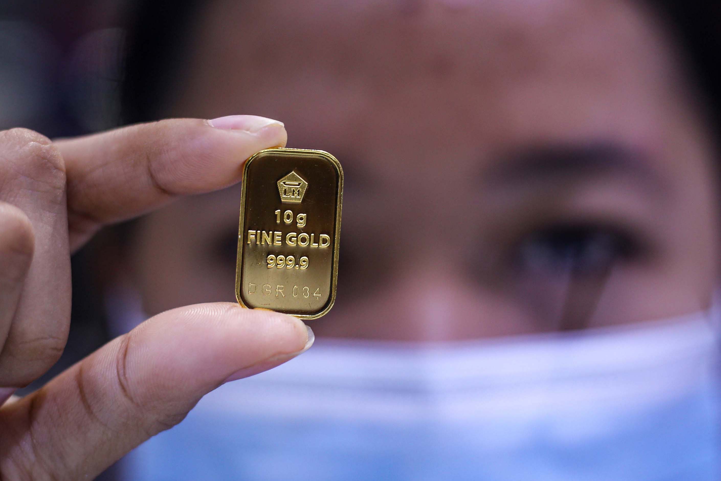 Seorang pegawai menunjukkan kepingan emas di toko perhiasan,Kota Tangerang, Banten, Jumat (25/9/2020).