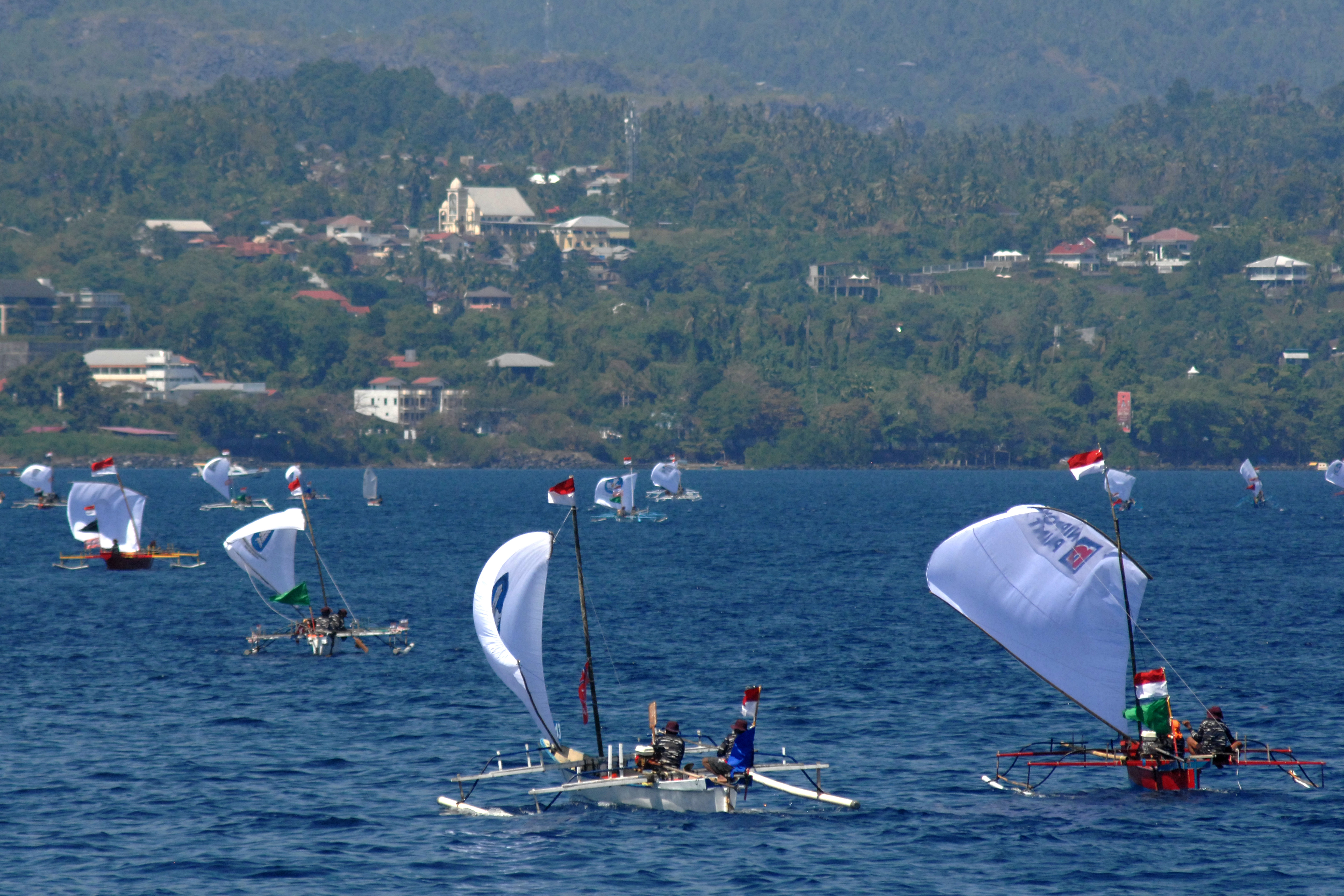 Puluhan perahu layar tradisional berlayar lintas (sail pass) pada pembukaan kompetisi olahraga air di pesisir perairan teluk Manado