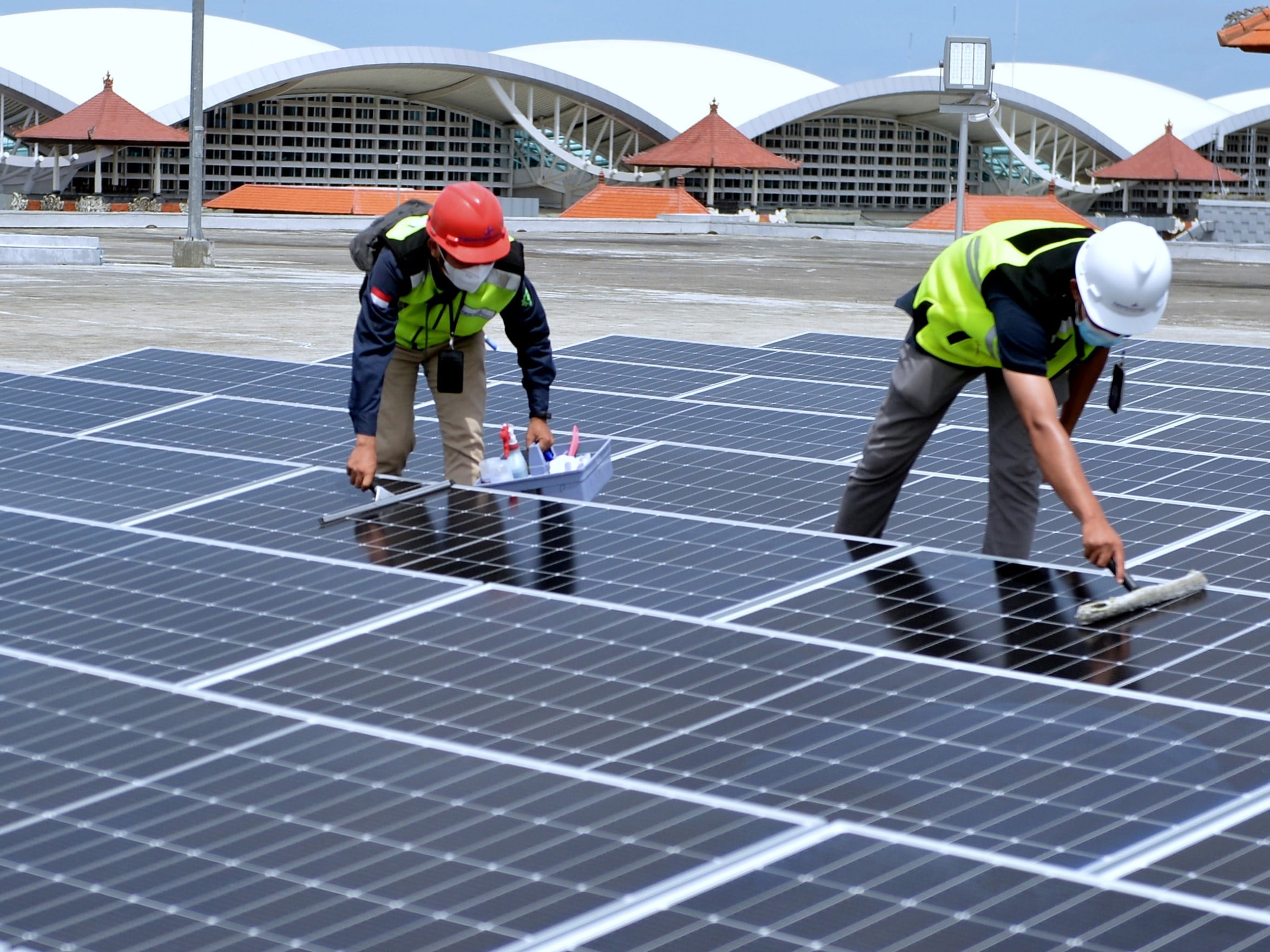 Petugas melakukan perawatan panel surya pada pembangkit listrik tenaga surya (PLTS) di Bandara I Gusti Ngurah Rai, Badung, Bali.