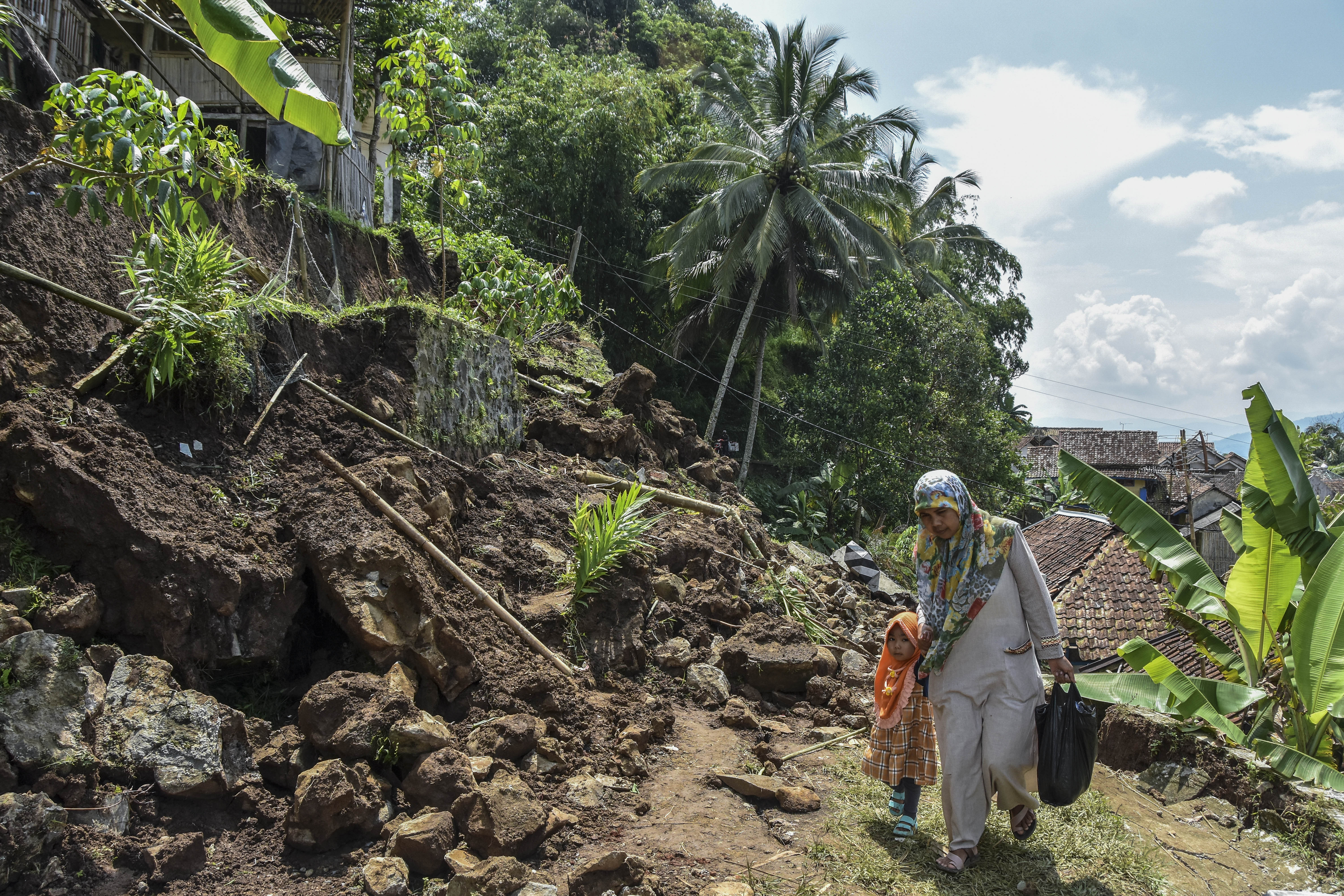 Warga melewati rumah yang terdampak longsor di Tasikmalaya