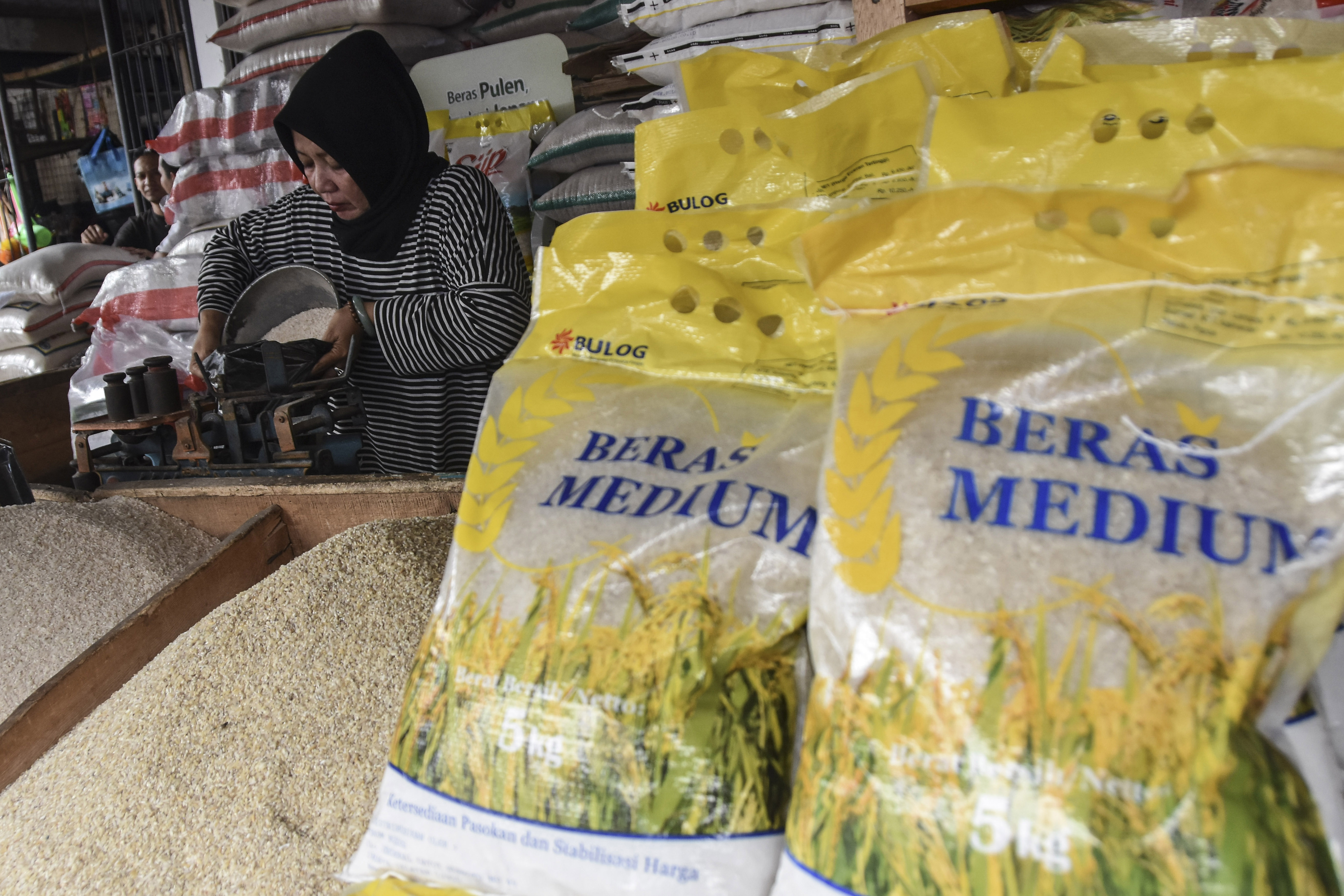Pedagang beras tengah melayani seorang pembeli 