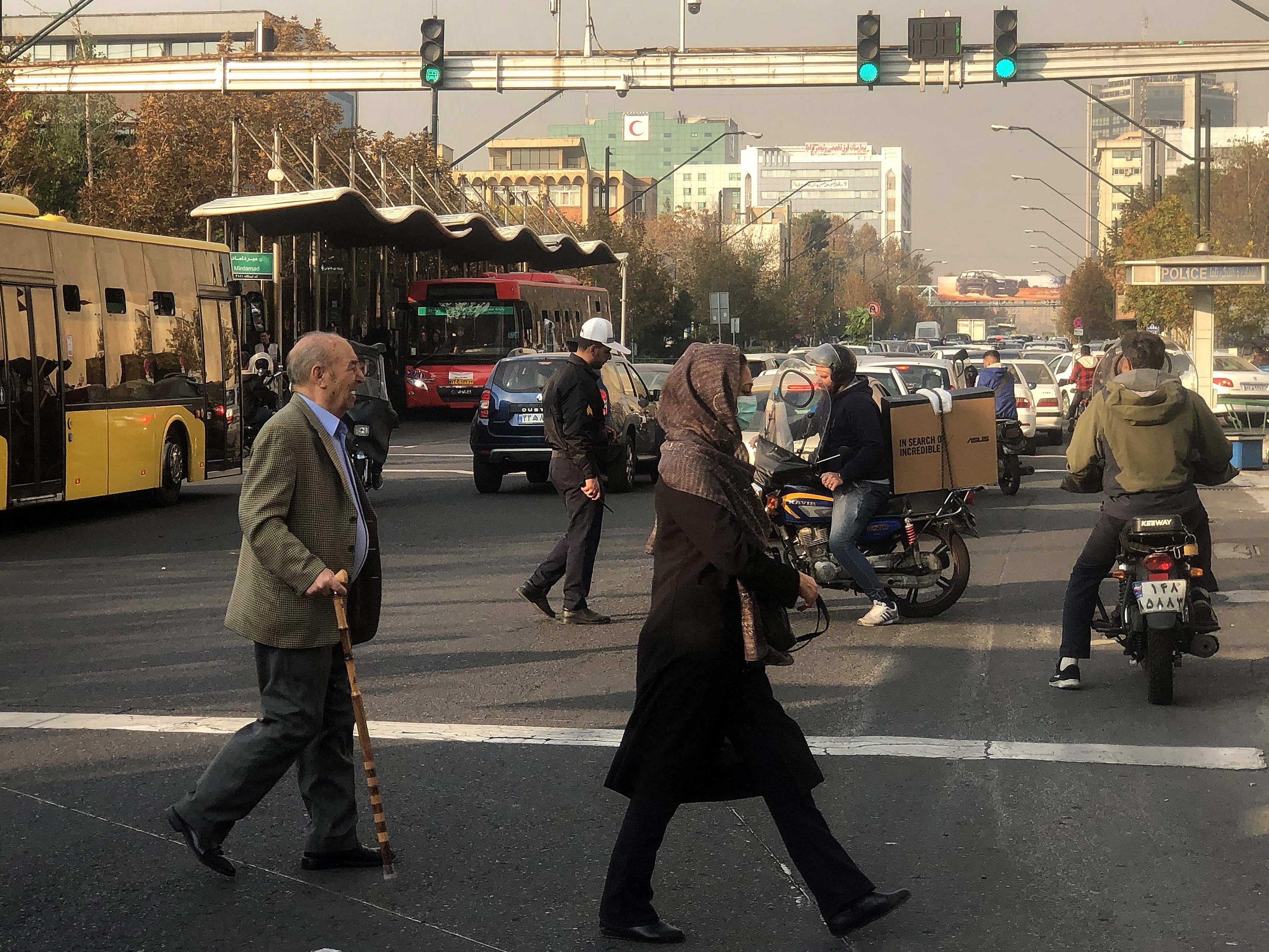 Orang-orang melintasi jalan utama di Teheran pada 14 November 2023 di tengah lapisan kabut tebal yang menyelimuti ibu kota Iran. 
