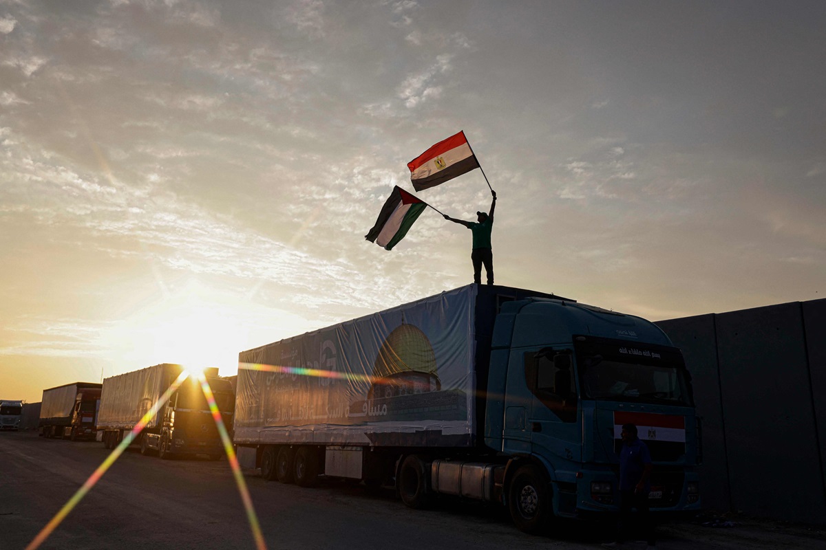 Seorang pengemudi mengibarkan bendera Mesir dan Palestina di atas truk yang membawa bantuan ke Jalur Gaza.
