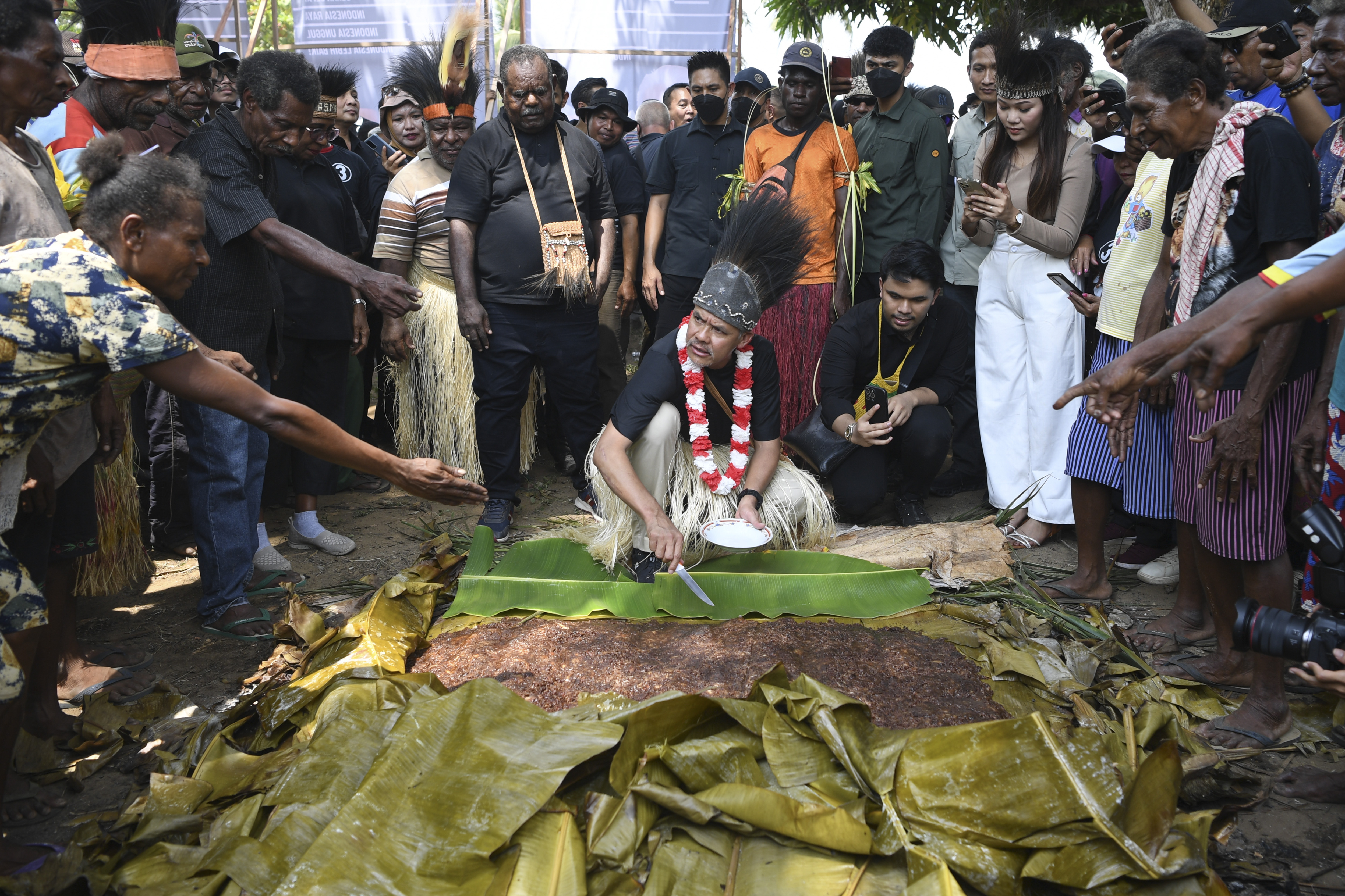 Calon presiden nomor urut tiga Ganjar Pranowo (tengah) memotong sagu kelapa saat melakukan kampanye perdana di Distrik Semangga, Merauke,