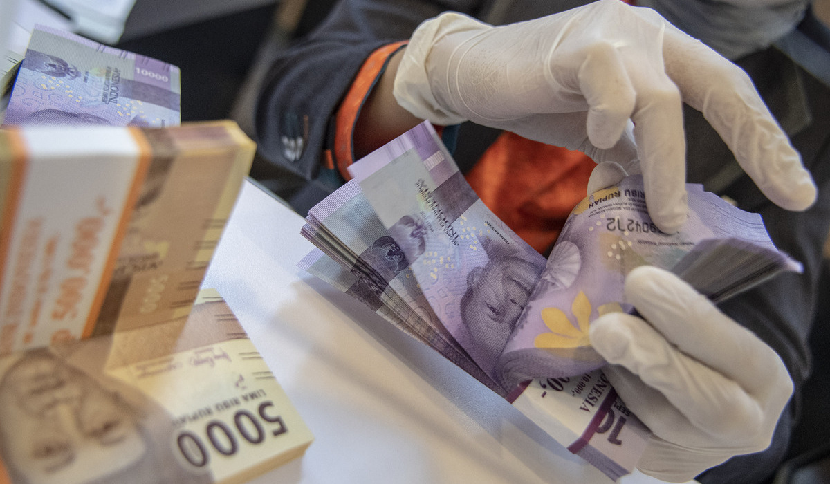 Petugas bank menghitung uang pecahan rupiah.