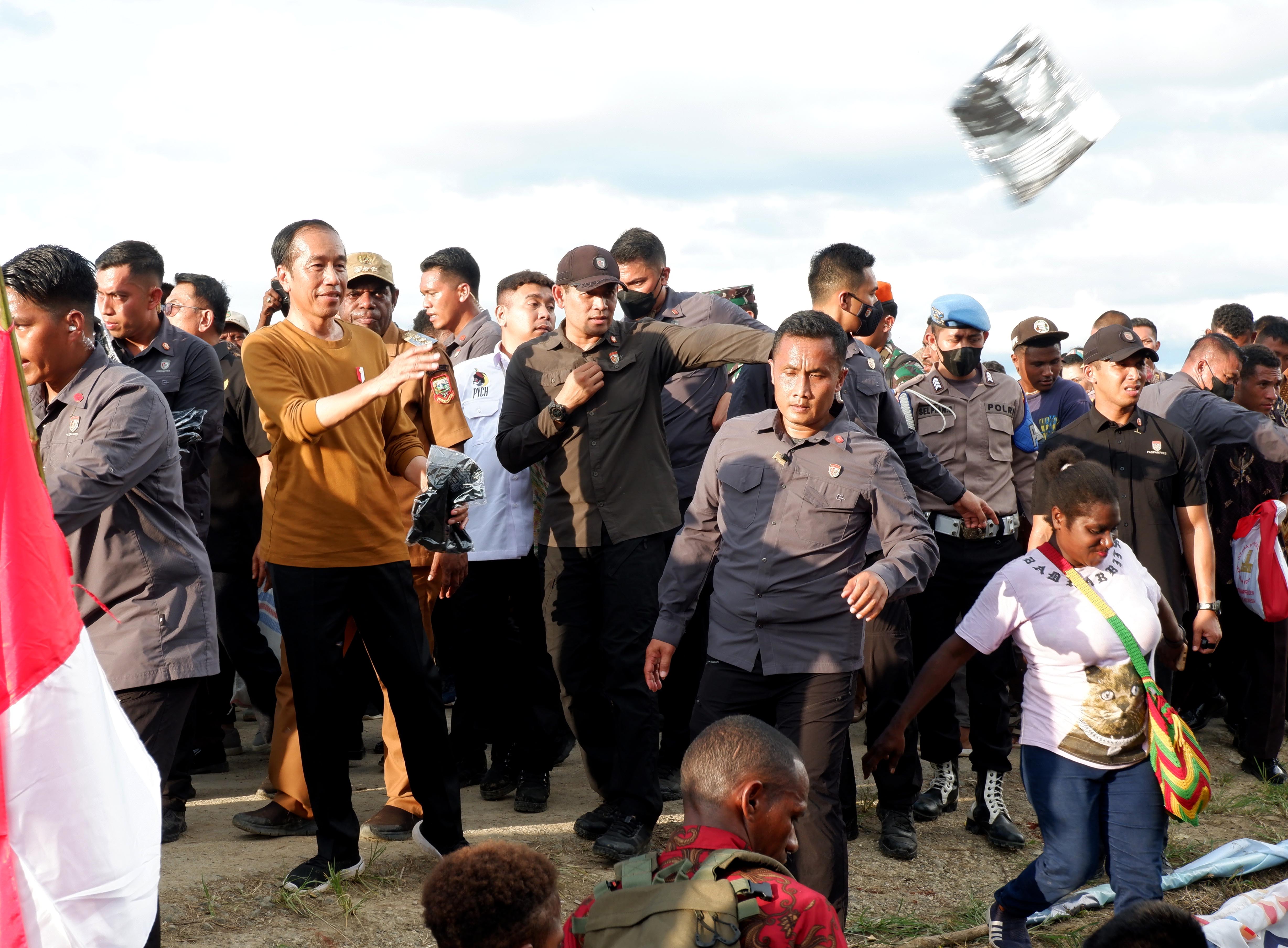 Presiden Joko Widodo (kiri) menberikan baju ketika meninjau lumbung pangan di Kampung Wambes, Distrik Mannem, Keerom, Papua.