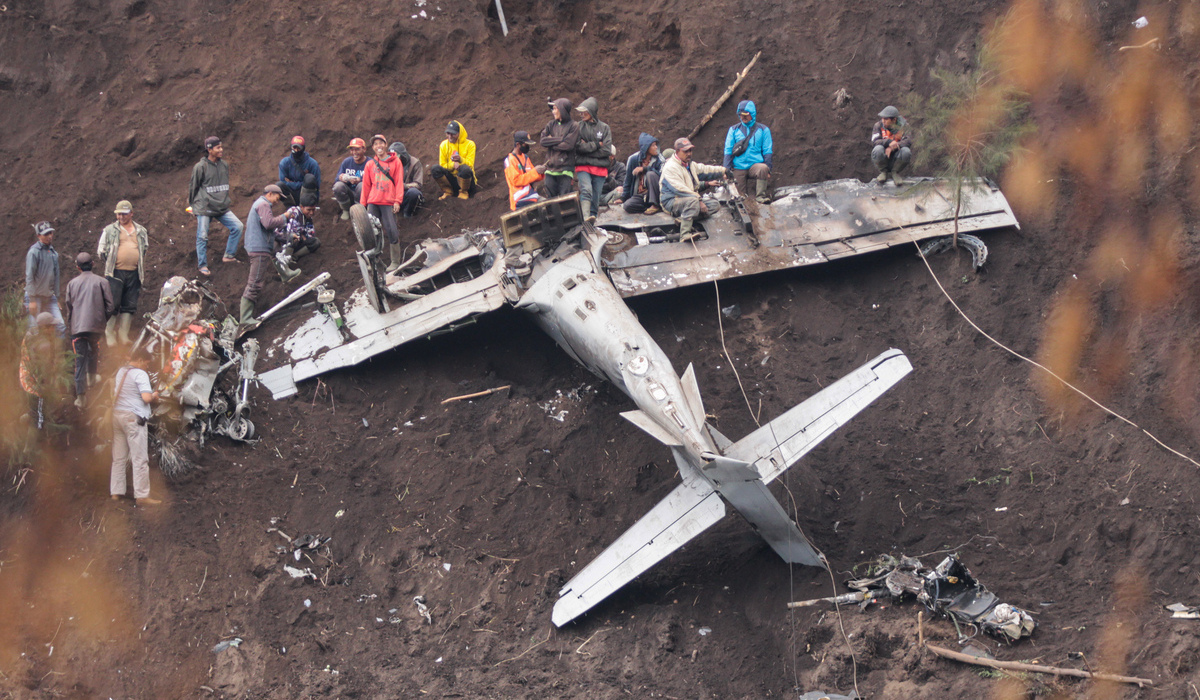 Warga berada di dekat bangkai pesawat tempur taktis EMB-314 Super Tucano TNI AU yang mengalami kecelakaan di Pasuruan, Jawa Timur.