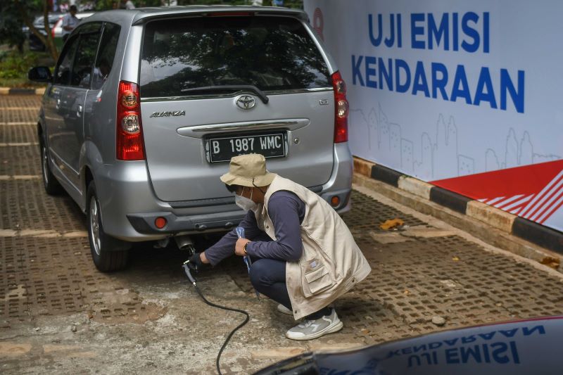 Petugas sedang melakukan uji emisi terhadap sebuah mobil.