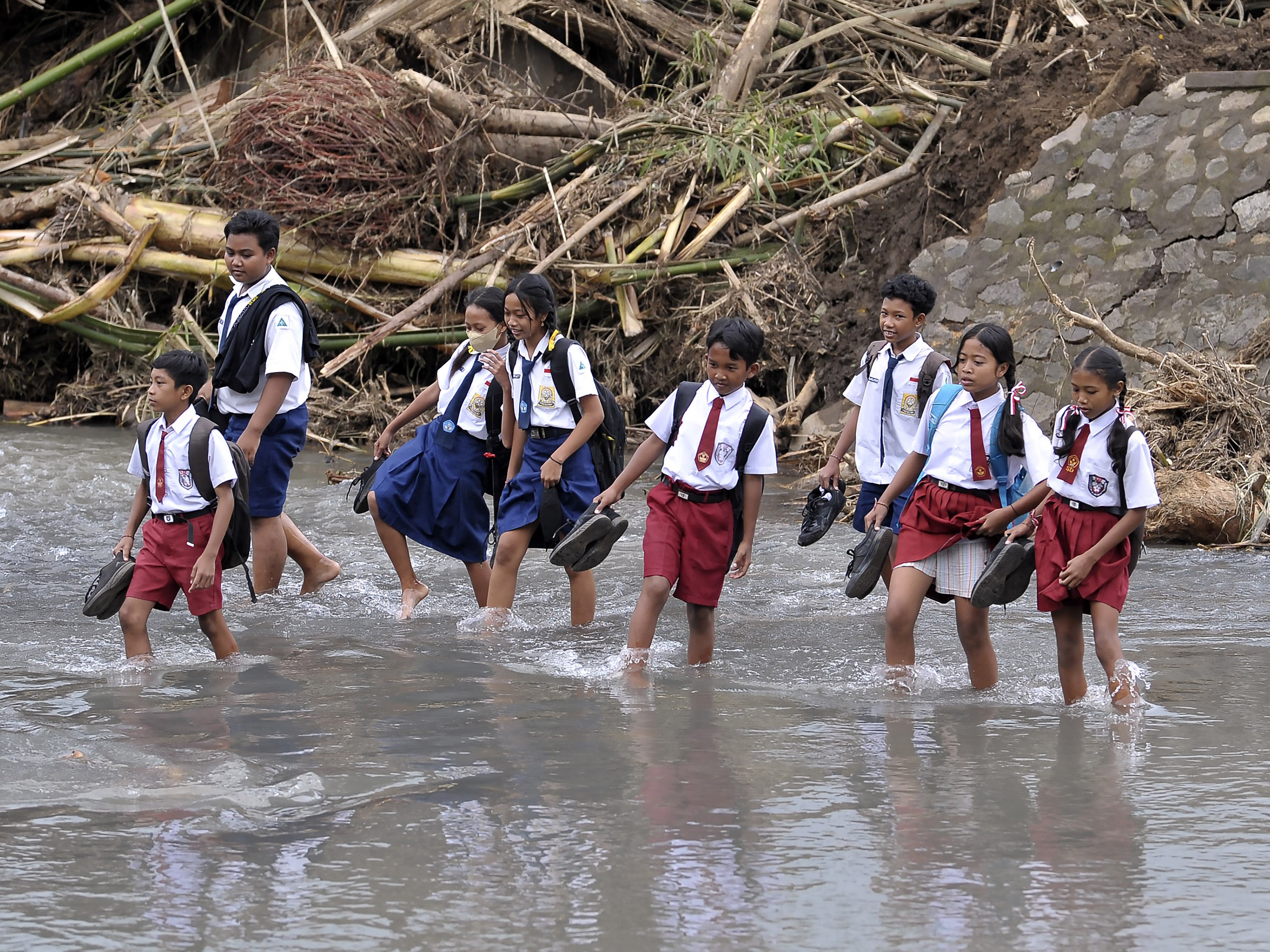 Siswa menyeberangi sungai pascabanjir bandang di Dusun Sekar Kejula Kelod, Desa Yehembang Kauh, Jembrana, Bali, Oktober 2022.