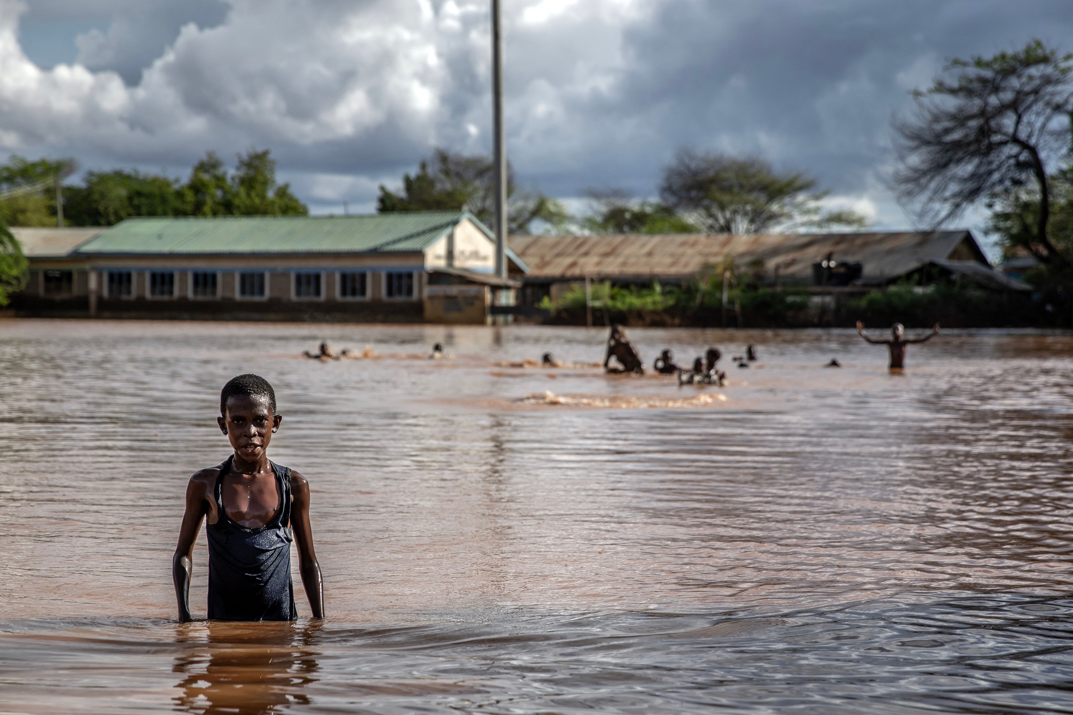 Seorang anak laki-laki berjalan menerobos banjir yang melanda Kenya, Senin (20/11).