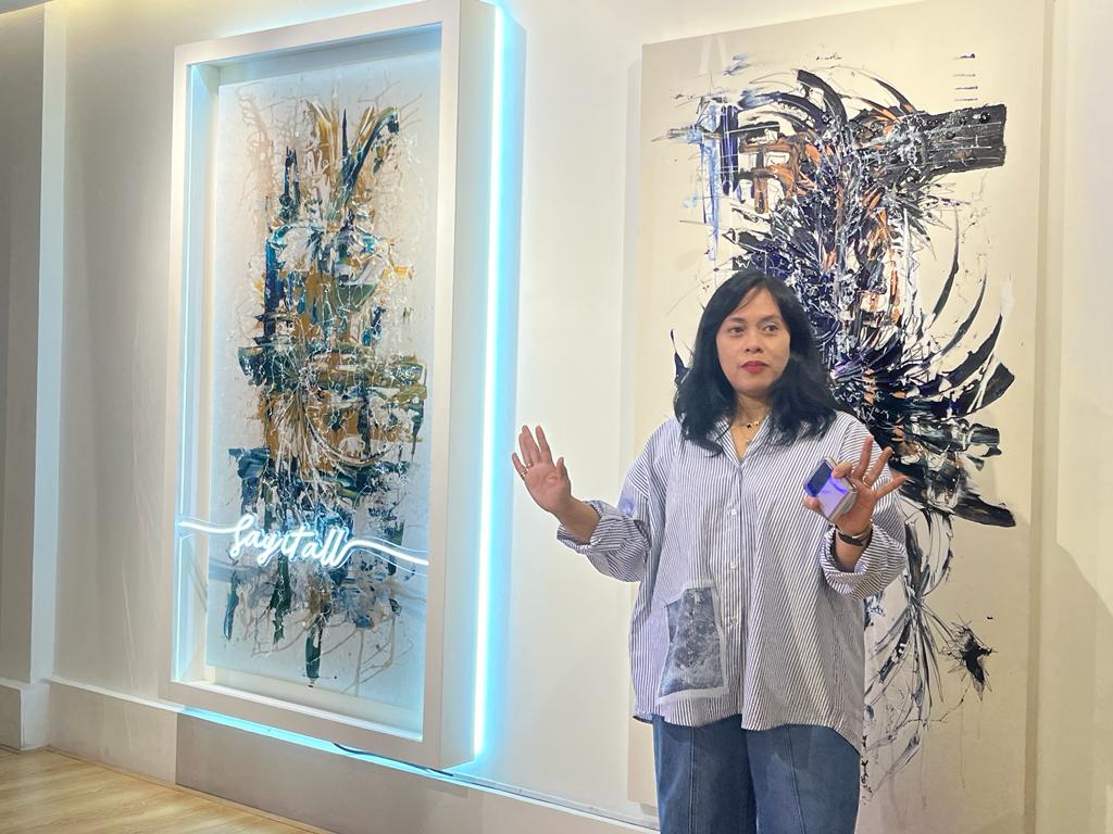 Seniman Laila Azra dengan latar karya seninya yang dipamerkan di Artsphere Gallery, Jakarta Selatan.