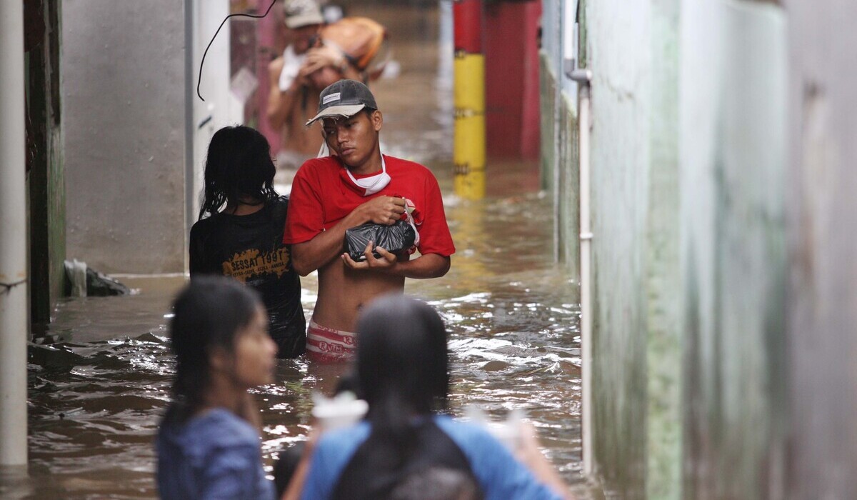 Warga beraktivitas di tengah banjir yang mengepung Kebon Pala, Kecamatan Jatinegara, Jakarta Timur.
