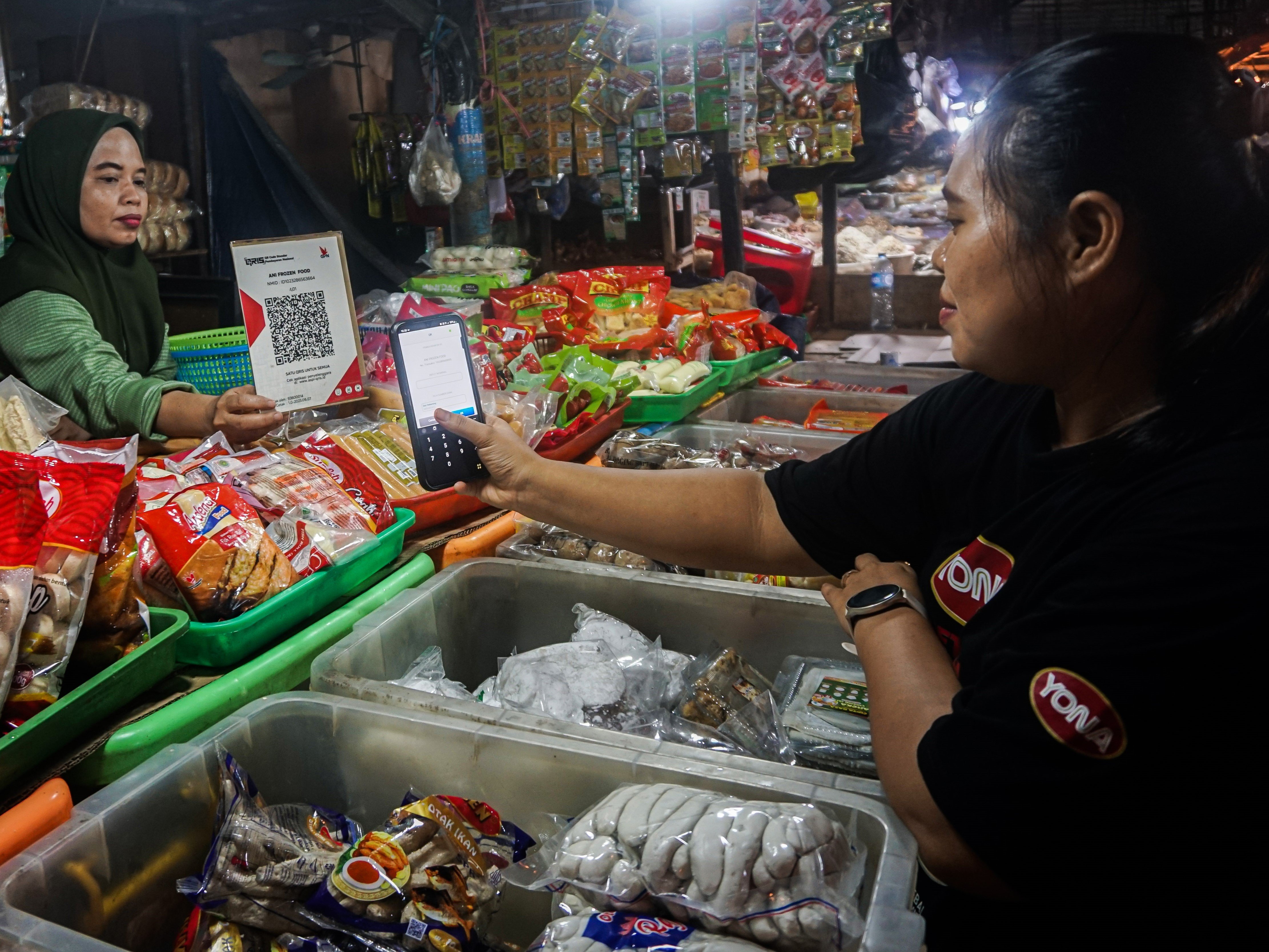 Pembeli melakukan pembayaran secara digital menggunakan Quick Response Code Indonesian Standard (QRIS) di Pasar Tradisional Pasar Minggu.