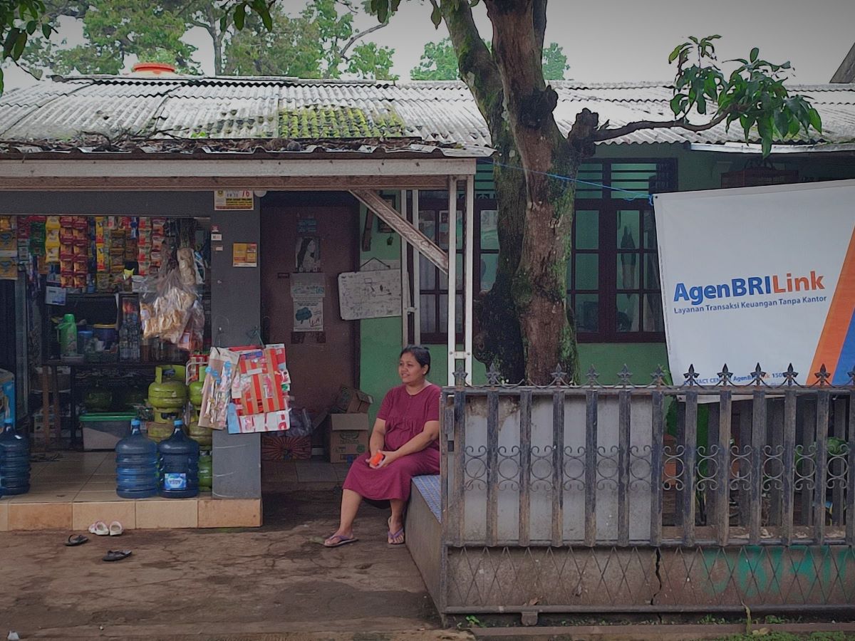 Nia sedang duduk di depan warungnya.