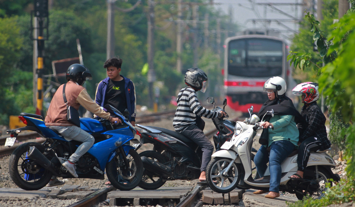Pengendara sepeda motor melintasi perlintasan sebidang yang dijaga oleh warga secara swadaya di Tebet, Jakarta.