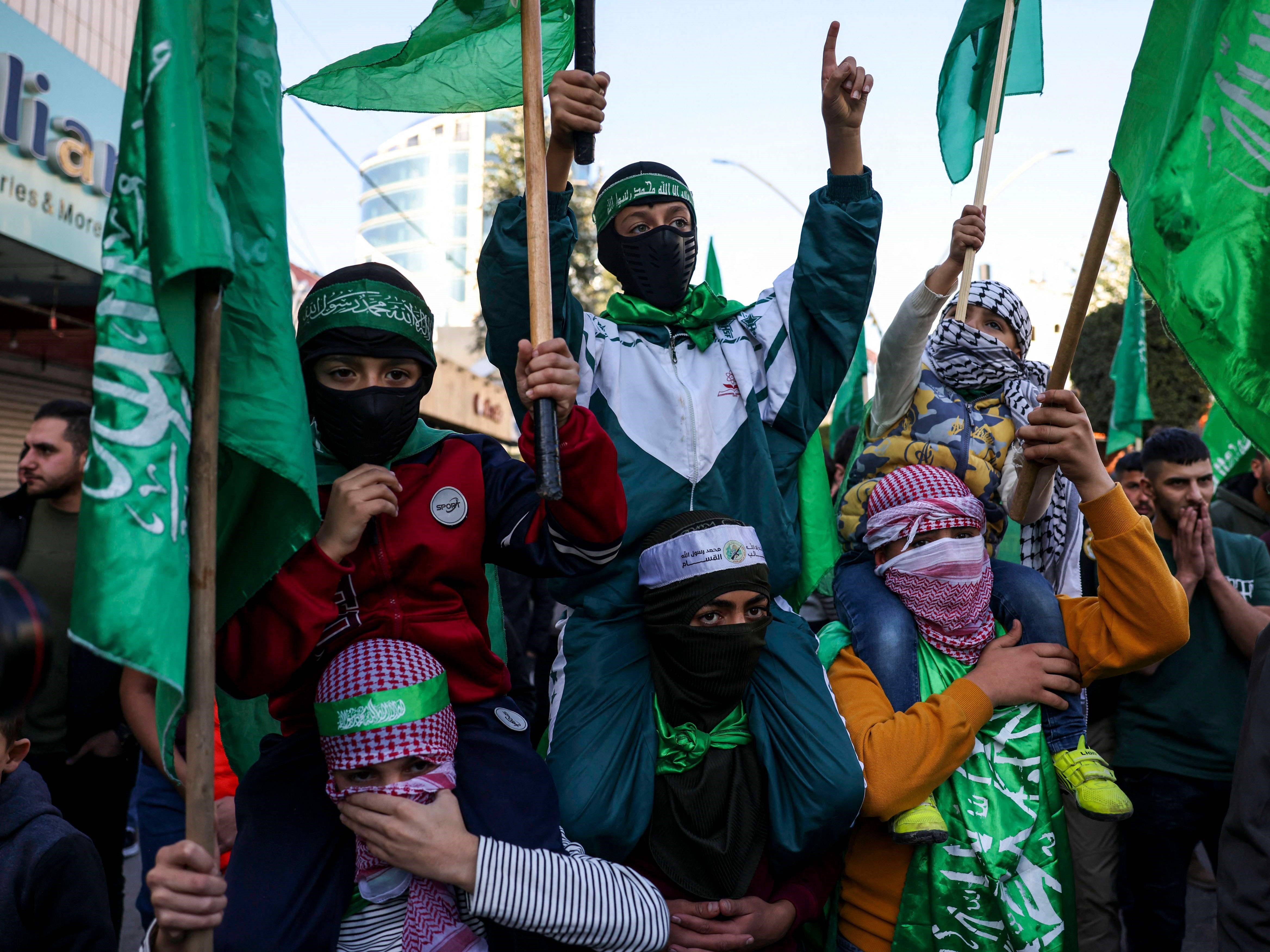 Pemuda Palestina mengenakan topeng dan membawa bendera Hamas selama unjuk rasa mendukung Jalur Gaza di kota Hebron, Tepi Barat.