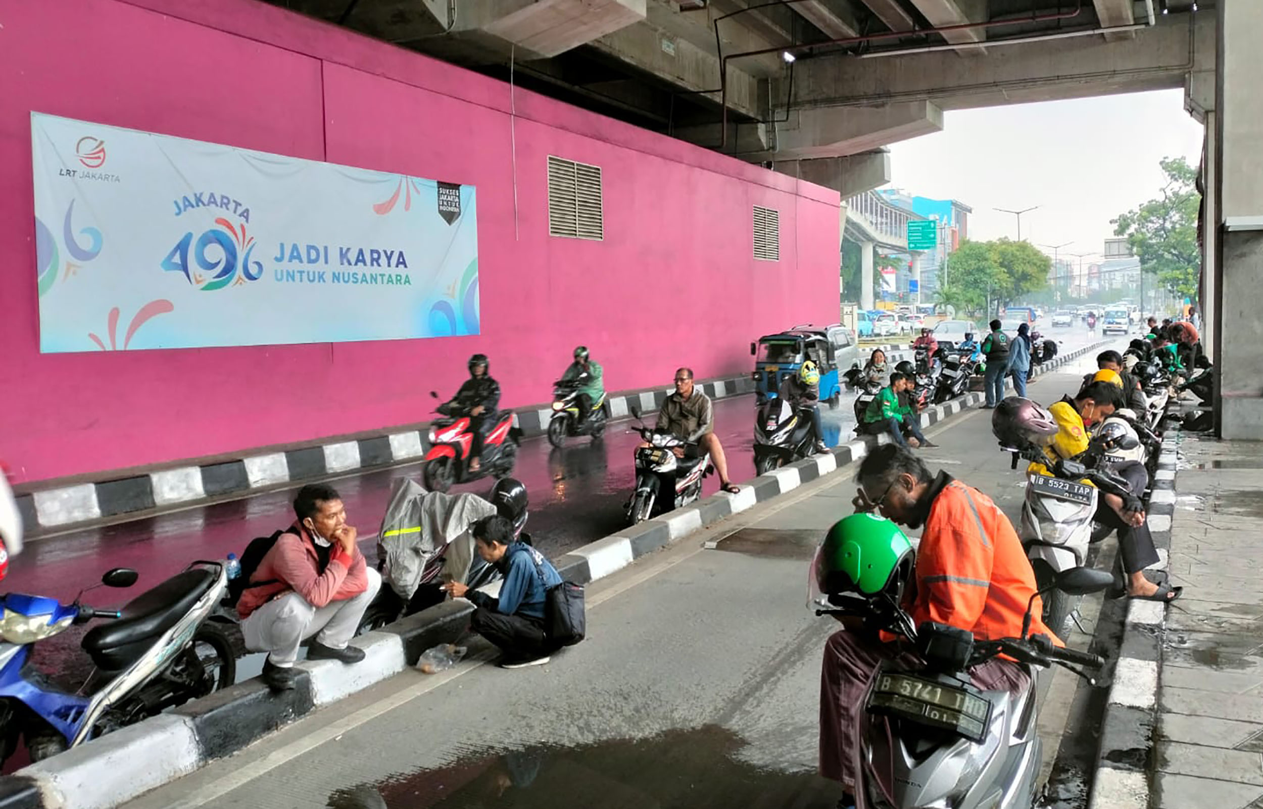 Pengendara motor berhenti dan berteduh di sepanjang marka jalan
