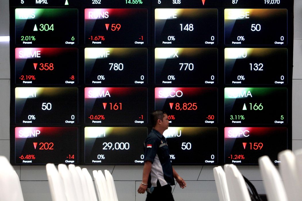 Pekerja melintasi papan-papan elektronik berisi data pergerakan bursa saham di Bursa Efek Indonesia (BEI), Jakarta
