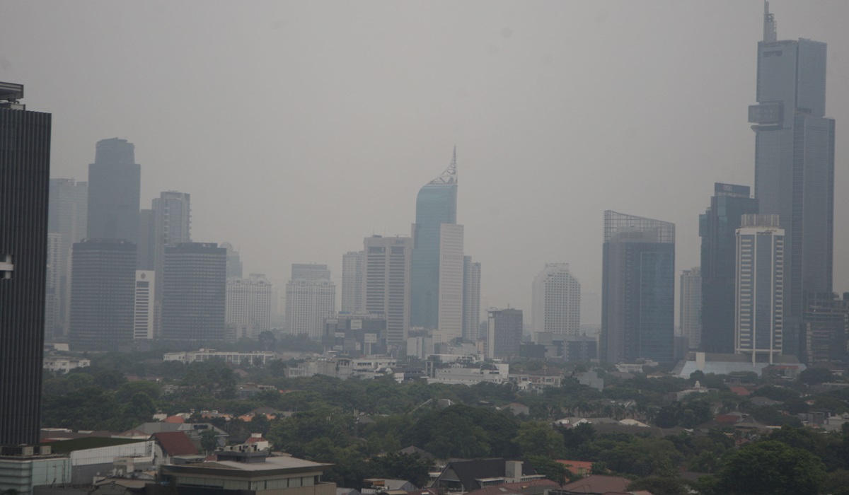 Lanskape gedung bertingkat yang diselimuti kabut polusi udara di Jakarta.