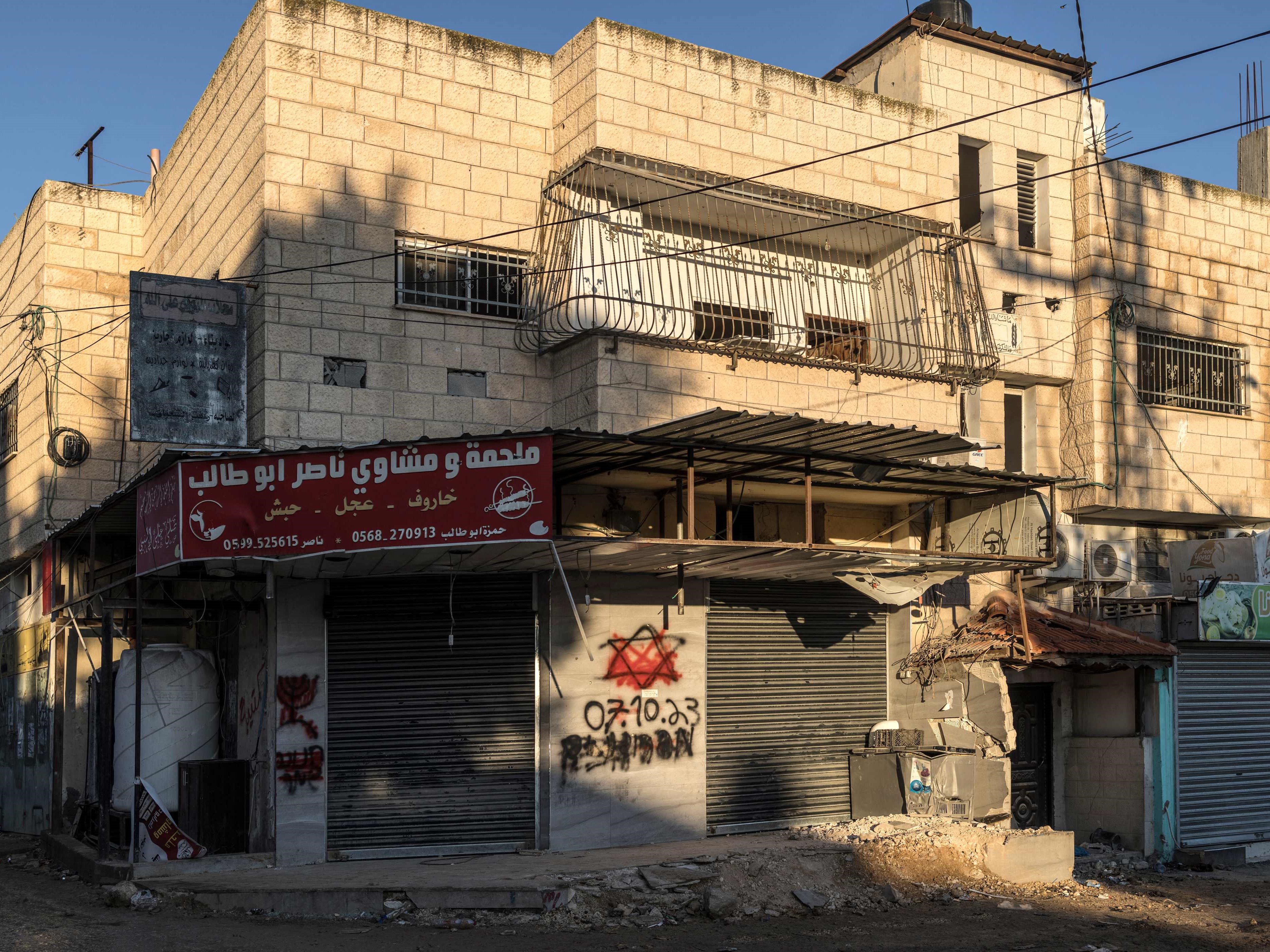 Cat merah menutupi Bintang Daud bertanggal 7 Oktober 2023 yang disemprotkan tentara Israel pada dinding rumah di kamp pengungsi Jenin.