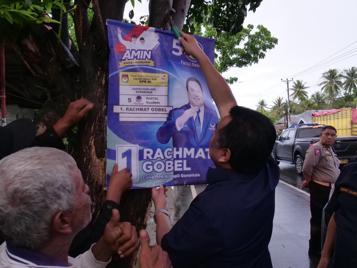 Rachmat Gobel mencopot poster kampanyenya sendiri yang terpasang di pohon. 