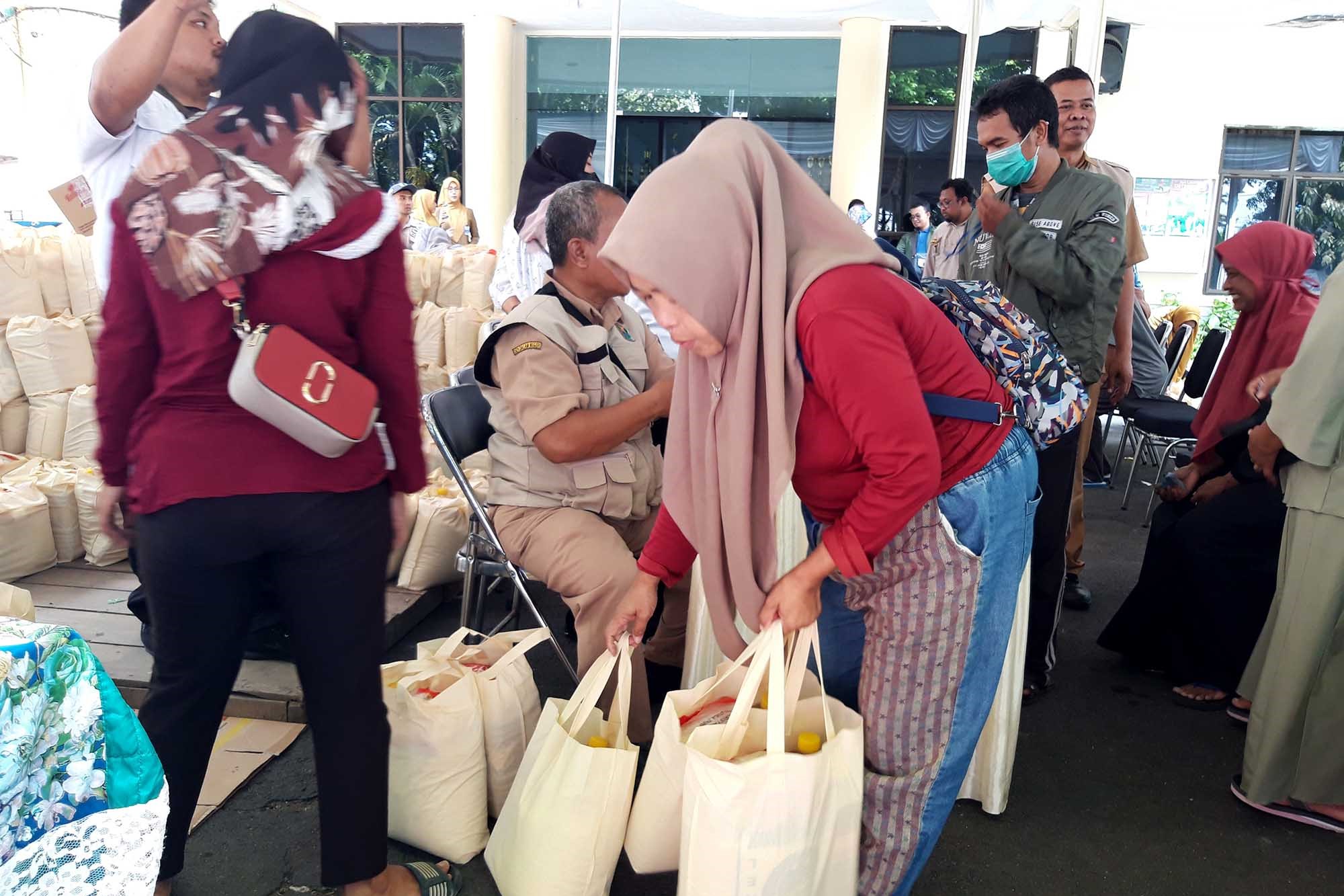 Petugas Dinas Koperasi Perindustrian dan Perdagangan Kota Malang, Jatim, melayani warga yang membeli paket bahan pokok saat pasar murah.