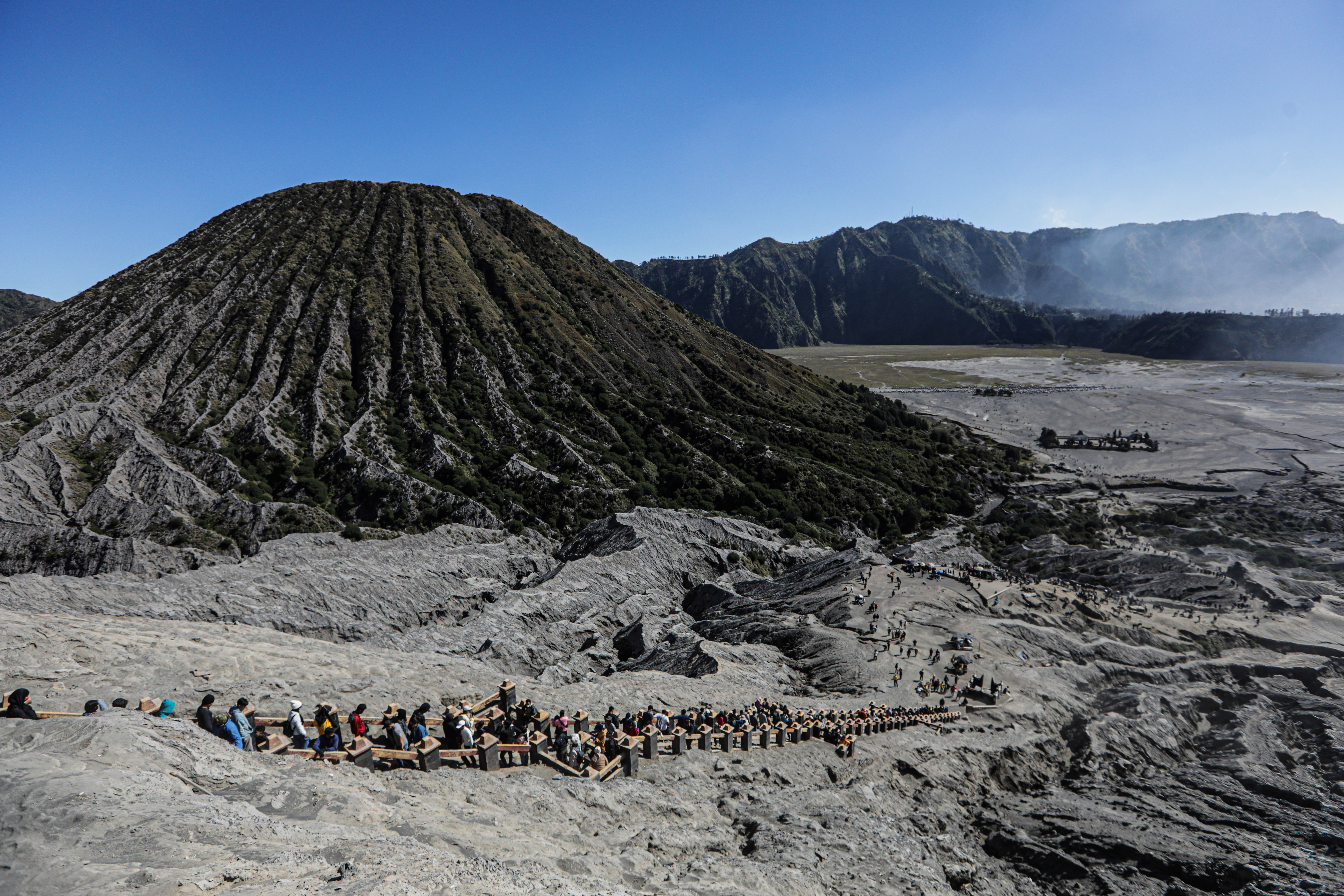 Wisatawan berjalan di bebatuan saat mengunjungi Air Terjun Madakaripura di Probolinggo, Jawa Timur, Juni 2023.