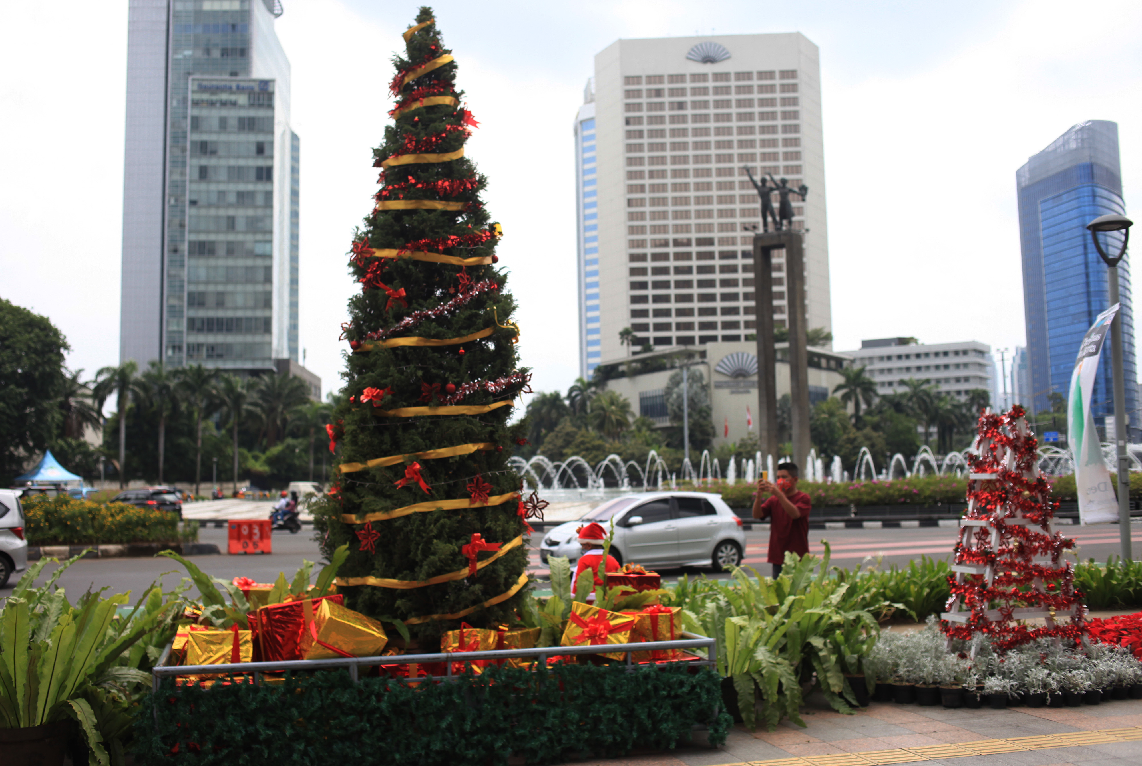 Seorang pria mengambil gambar hiasan pohon Natal yang terpajang di kawasan Bundaran Hotel Indonesia, Jakarta, Sabtu (25/12/2021).