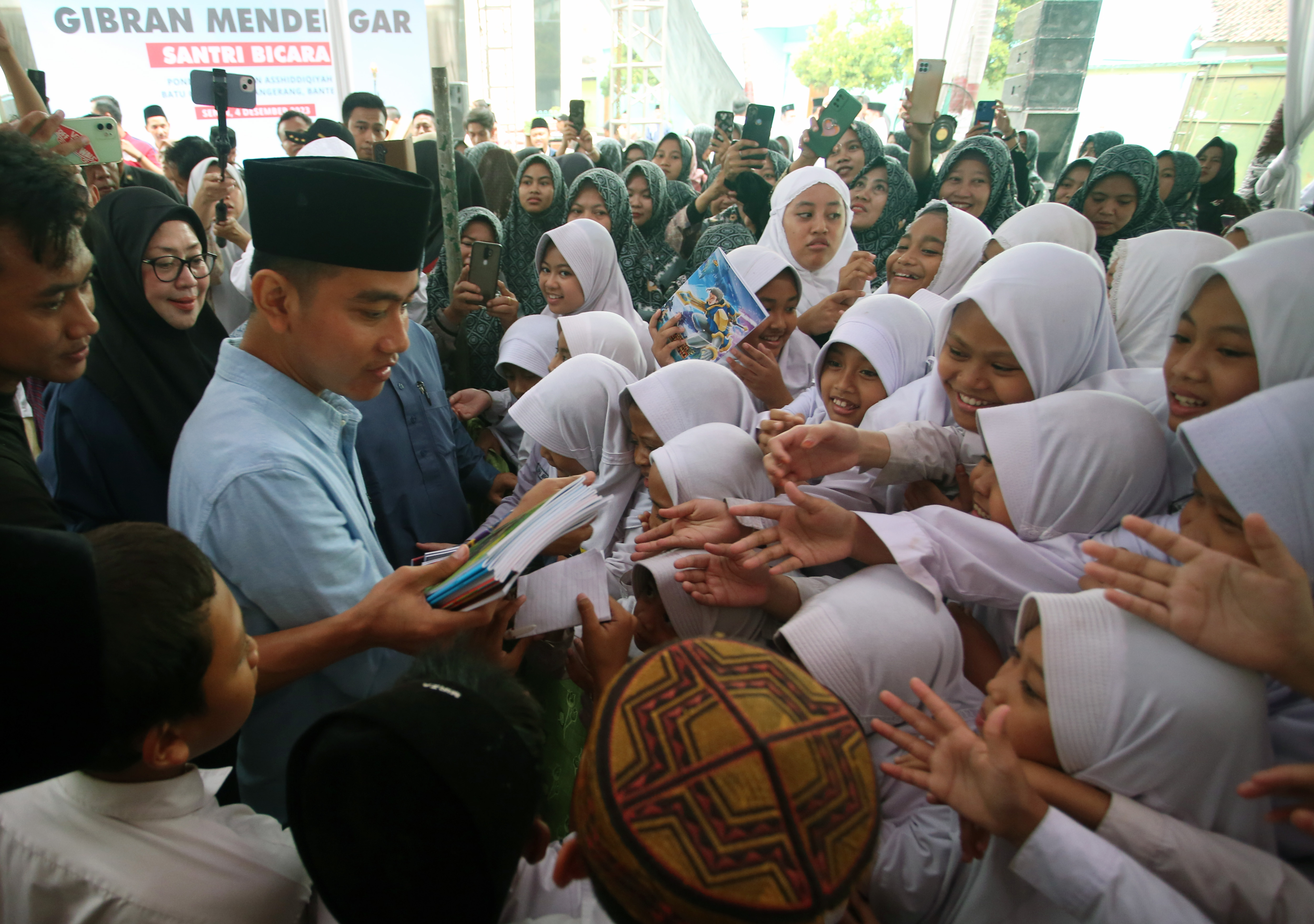 Calon wakil presiden nomor urut 2 Gibran Rakabuming Raka (kedua kiri) membagikan buku tulis