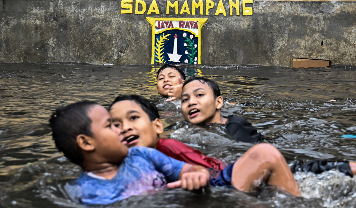 Anak-anak bermain saat banjir di Komplek Polri Pondok Karya, Mampang Prapatan, Jakarta.