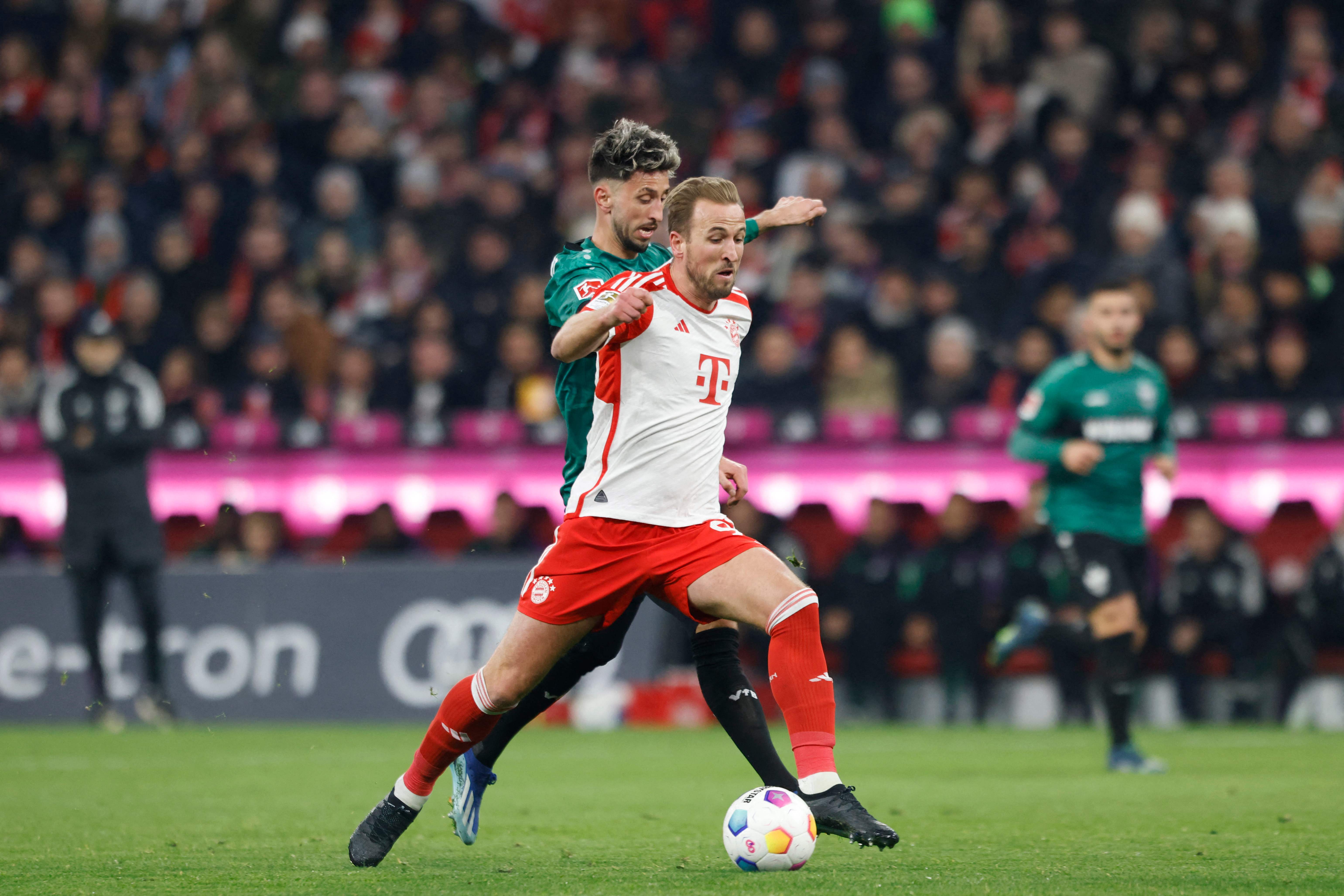 Penyerang Bayern Munich's asal Inggris #09 Harry Kane berebut bola dengan gelandang Jerman Stuttgart #16 Atakan Karazorduring.