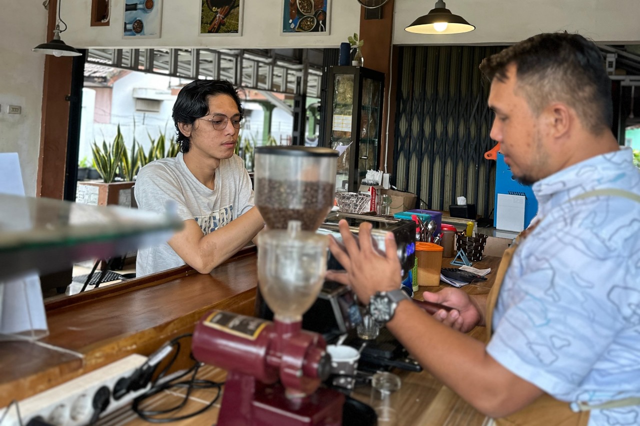 Deni Saputra meracik kopi untuk pelanggan di kafe 
