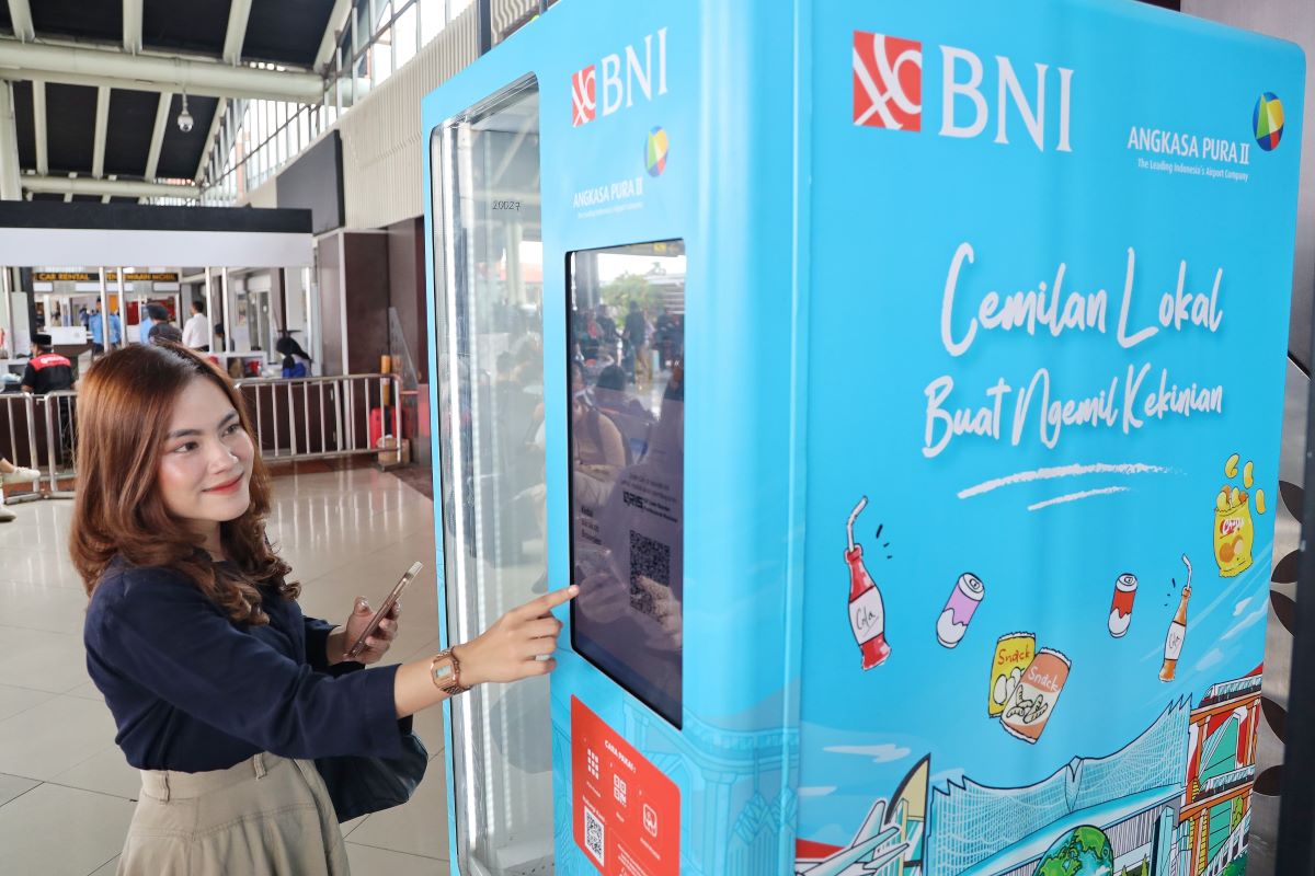 seorang warga menggunakan vending machine yang berisi produk UMKM.