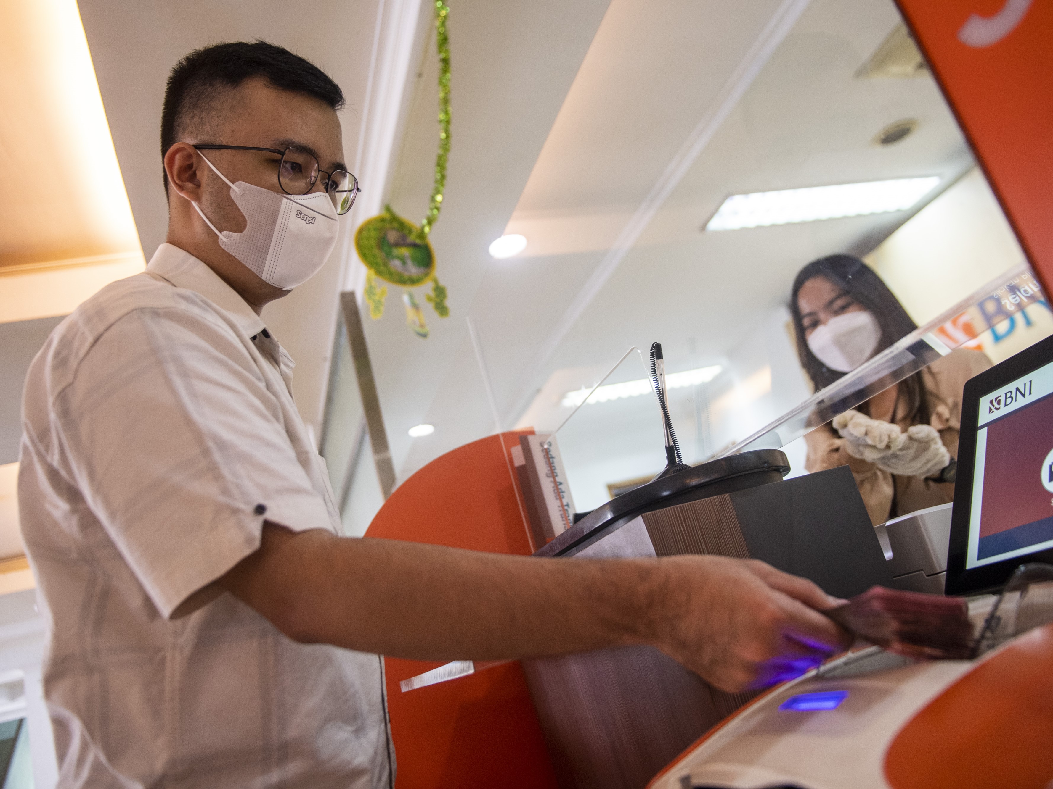 Nasabah melakukan setoran uang dengan mesin Teller Cash Recycle (TCR) saat operasional terbatas di Kantor Cabang BNI, Bandung, Jawa Barat.